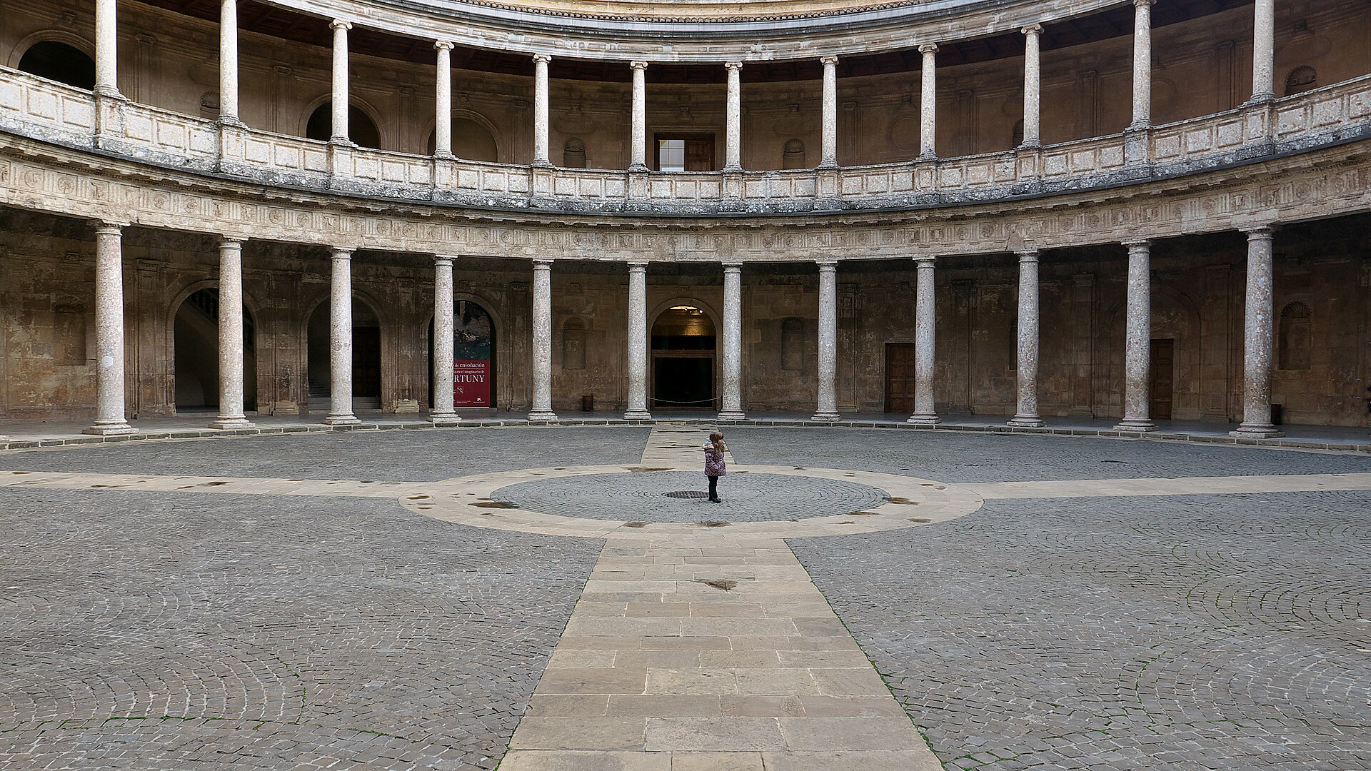 il cortile rotondo del palazzo di carlo v all’alhambra, con il doppio colonnato di pietra su due piani e il pavimento lastricato