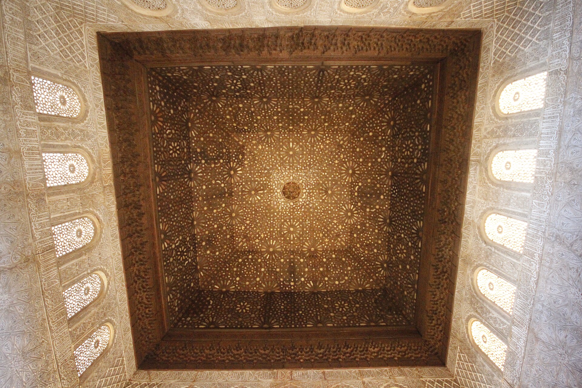 il soffitto di legno del salon de los embajadores dell’alhambra, un grande quadrato di legno a stelle intarsiate sopra finestre ad arco e pareti di stucco
