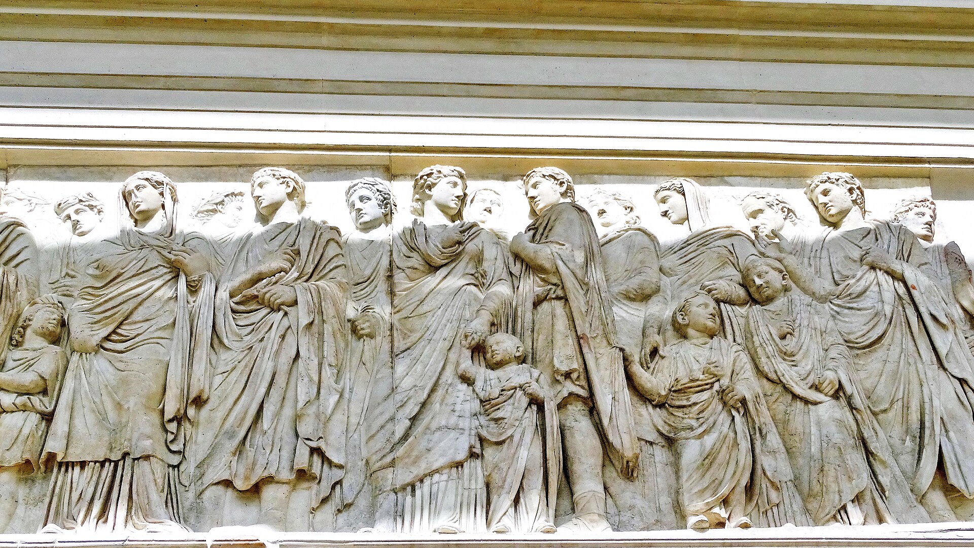 il fregio della processione sul lato sud dell ara pacis, con le figure togate in fila e due bambini aggrappati alle vesti degli adulti