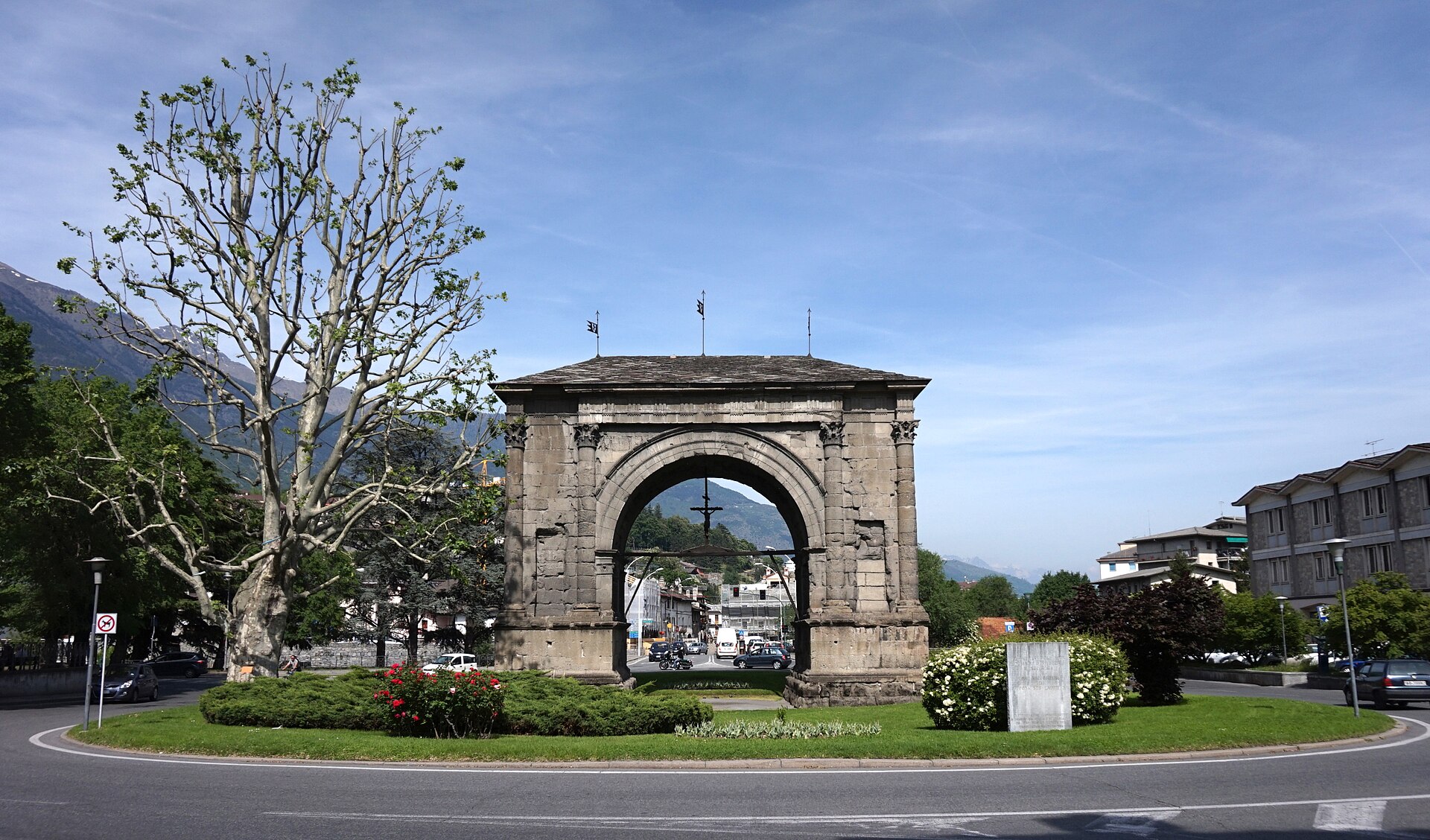 l arco di augusto ad aosta visto di fianco sulla rotonda, con il tetto in ardesia e le montagne dietro
