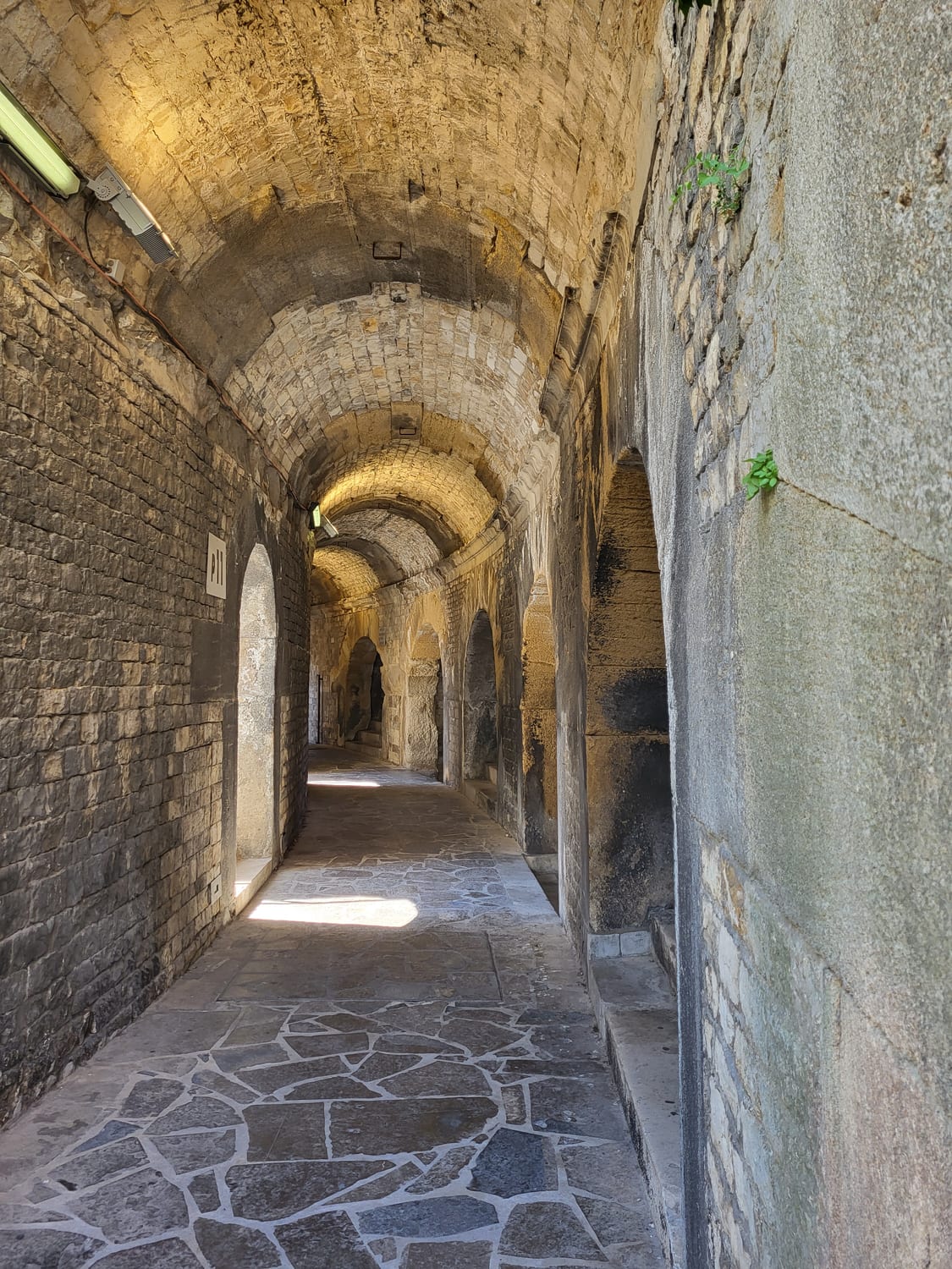 una galería anular cubierta de la Arena de Nimes, con su bóveda de cañón de piedra y la luz que entra por las aberturas laterales