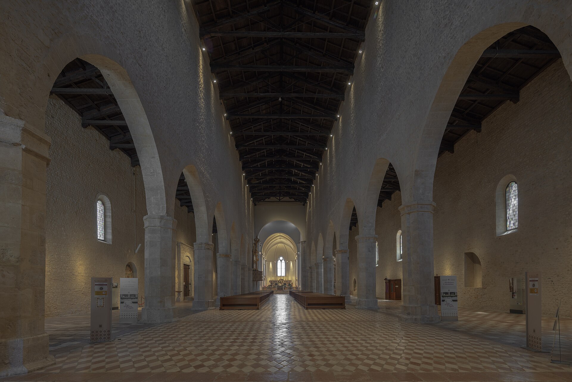 l interno a tre navate della basilica di collemaggio con pilastri ottagonali capriate di legno e pavimento a scacchi
