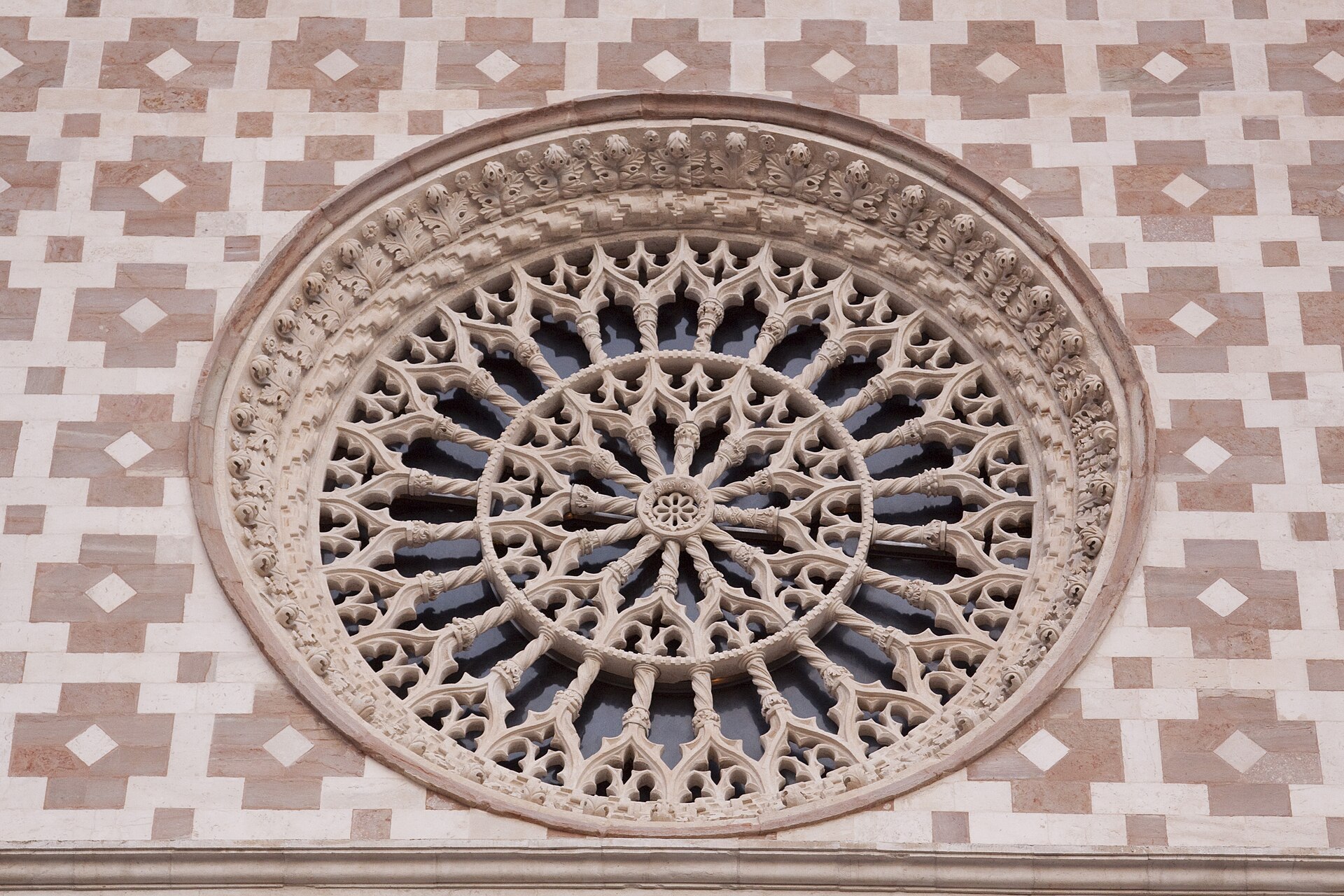 il rosone maggiore della basilica di collemaggio con il traforo di pietra a raggiera dentro il paramento a scacchi