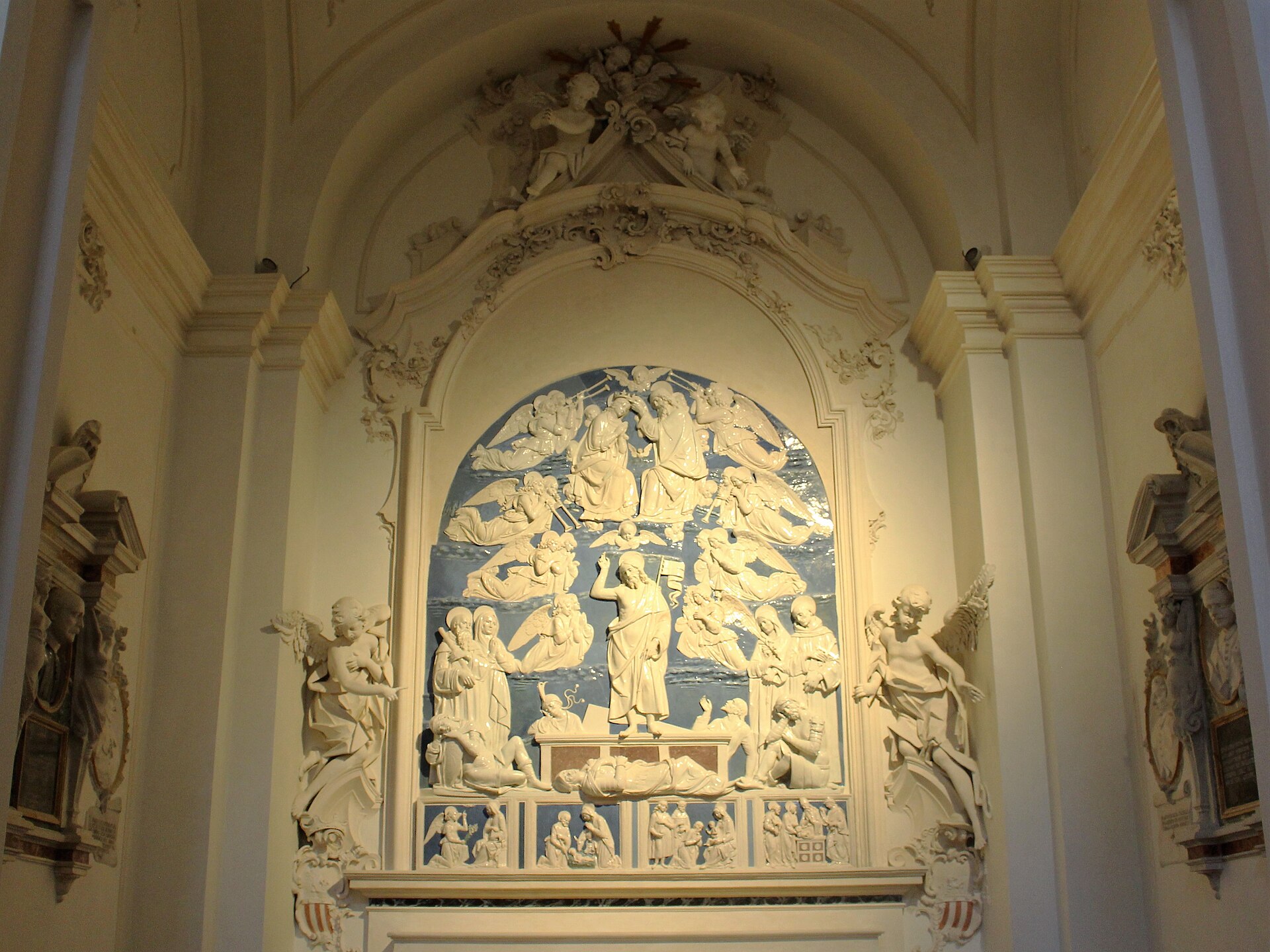 la resurrezione in terracotta invetriata di andrea della robbia con le figure bianche sul fondo azzurro dentro la cornice barocca