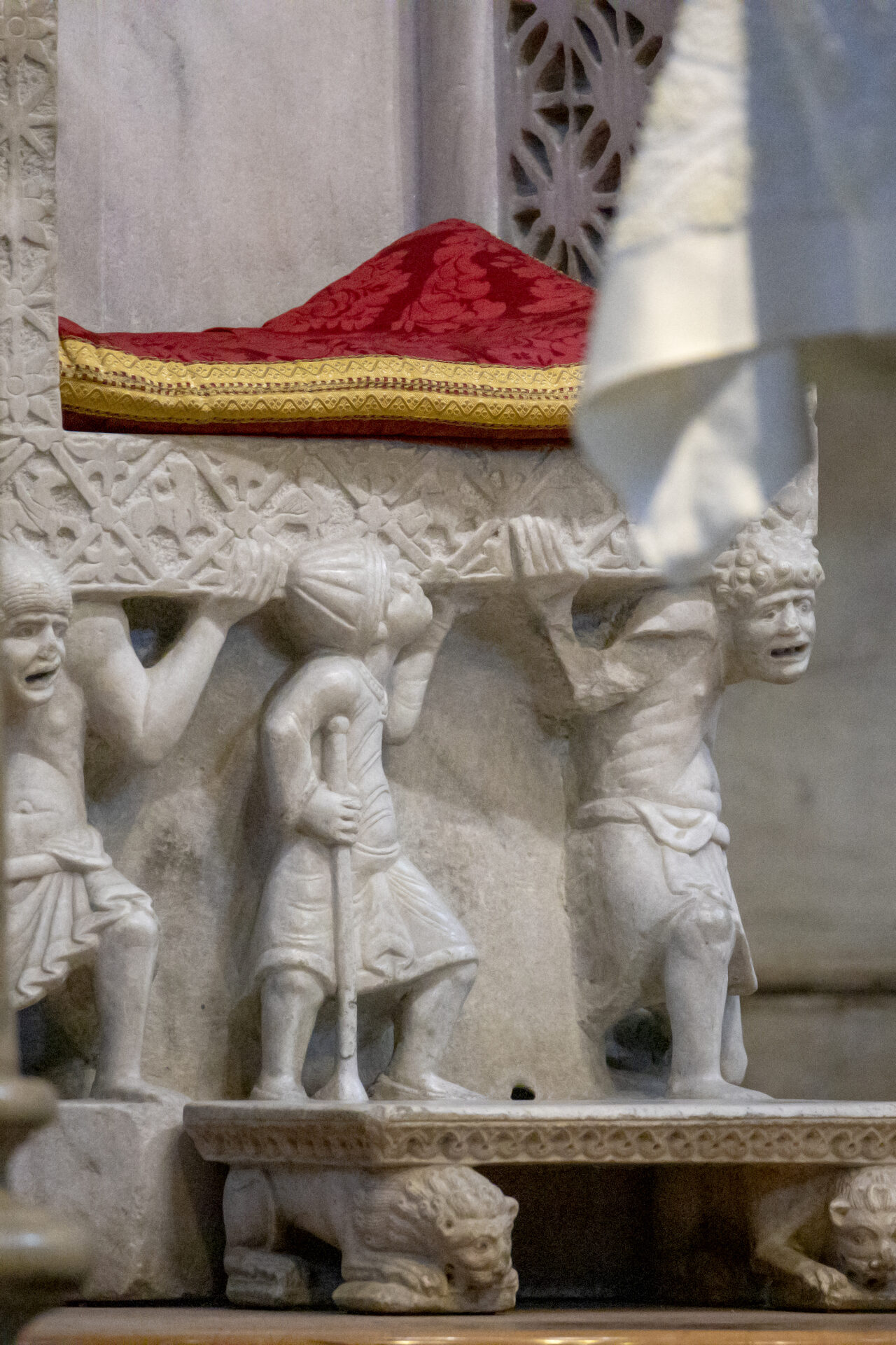 the three telamones carrying the cathedra of abbot elia in the basilica of san nicola in bari, their faces tight with effort