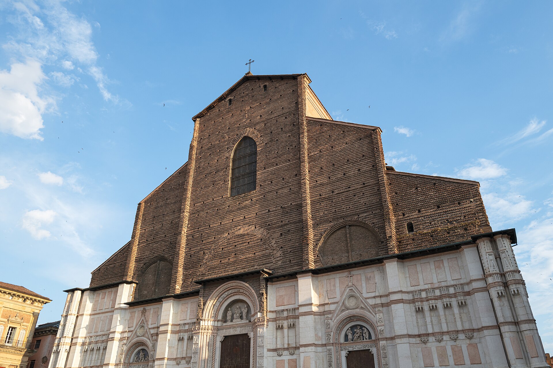 la facciata incompiuta della basilica di san petronio a bologna, con il rivestimento in marmo che si interrompe e il laterizio nudo sopra