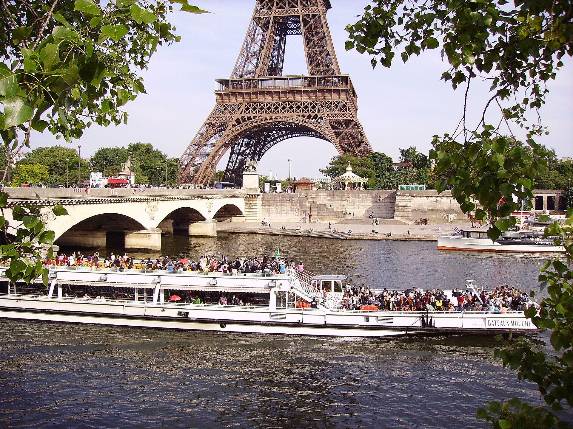 un bateau mouche carico di passeggeri sulla senna con la tour eiffel e il ponte d’iena sullo sfondo