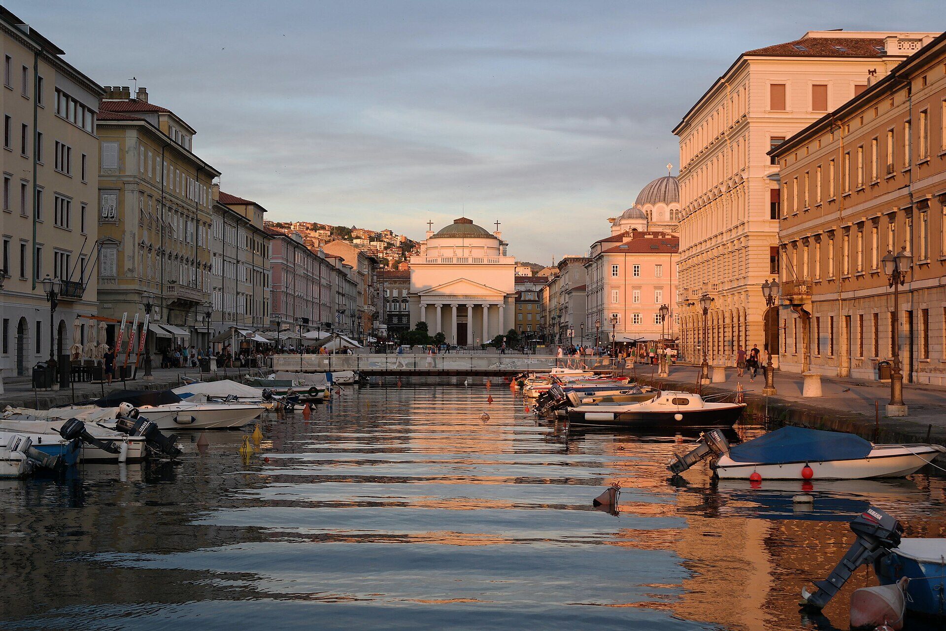il canal grande di trieste al tramonto con le barche ormeggiate la chiesa di sant antonio in fondo e la cupola di san spiridione a destra