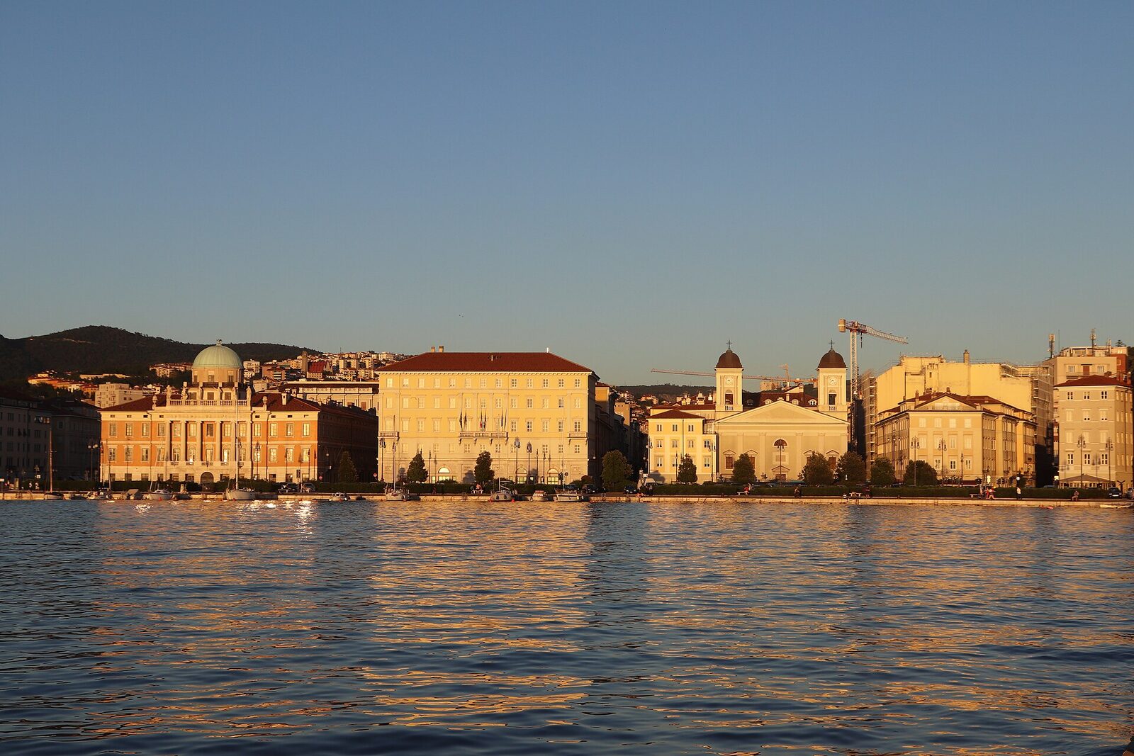 le rive di trieste al tramonto con palazzo carciotti a sinistra e i due campanili di san nicolo dei greci a destra