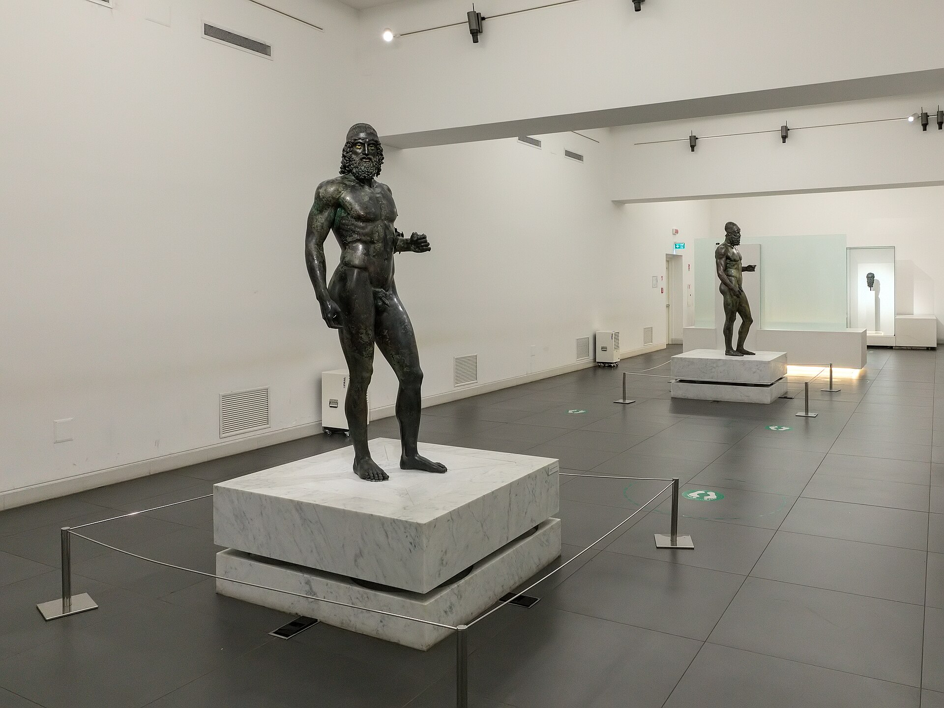 i due bronzi di riace nella sala del museo di reggio calabria sulle basi di marmo bianco