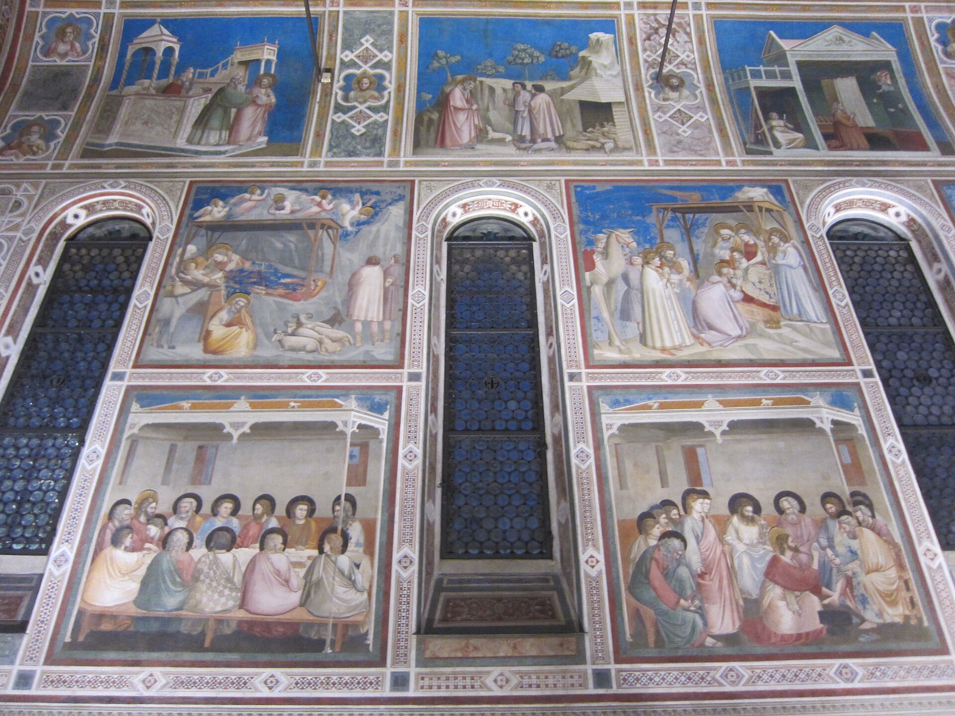 una parete della cappella degli scrovegni con le tre fasce di riquadri affrescati da giotto e il fondo blu