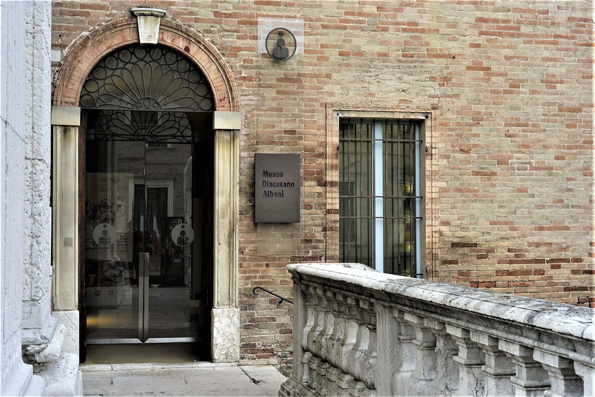 entrance of the albani diocesan museum in urbino with a brick portal and sign