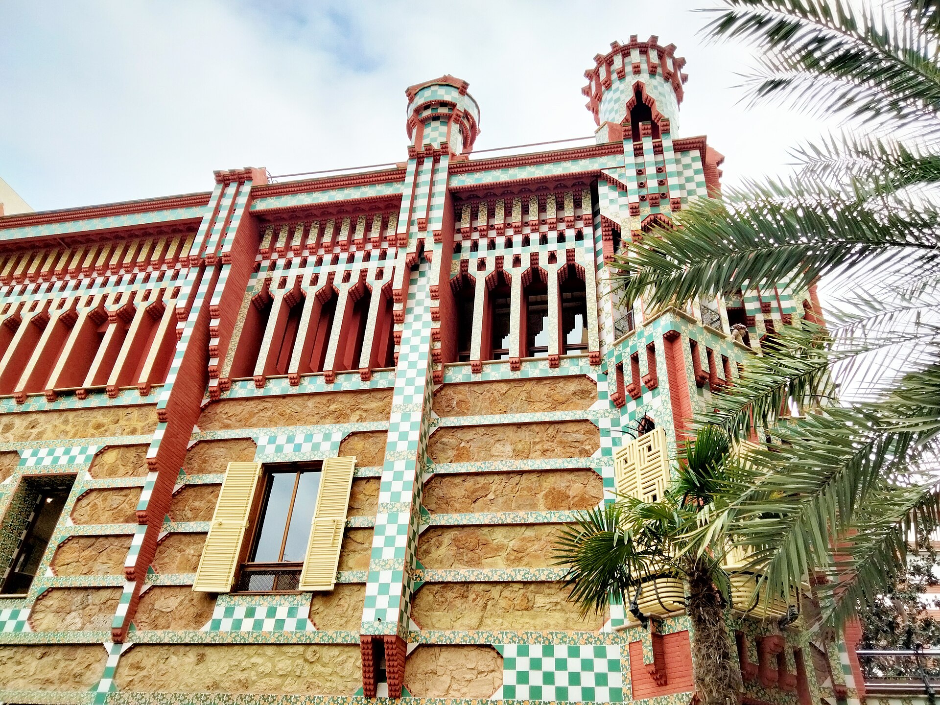 la facciata di casa vicens con le fasce di piastrelle verdi e bianche, i mattoni rossi e le torrette