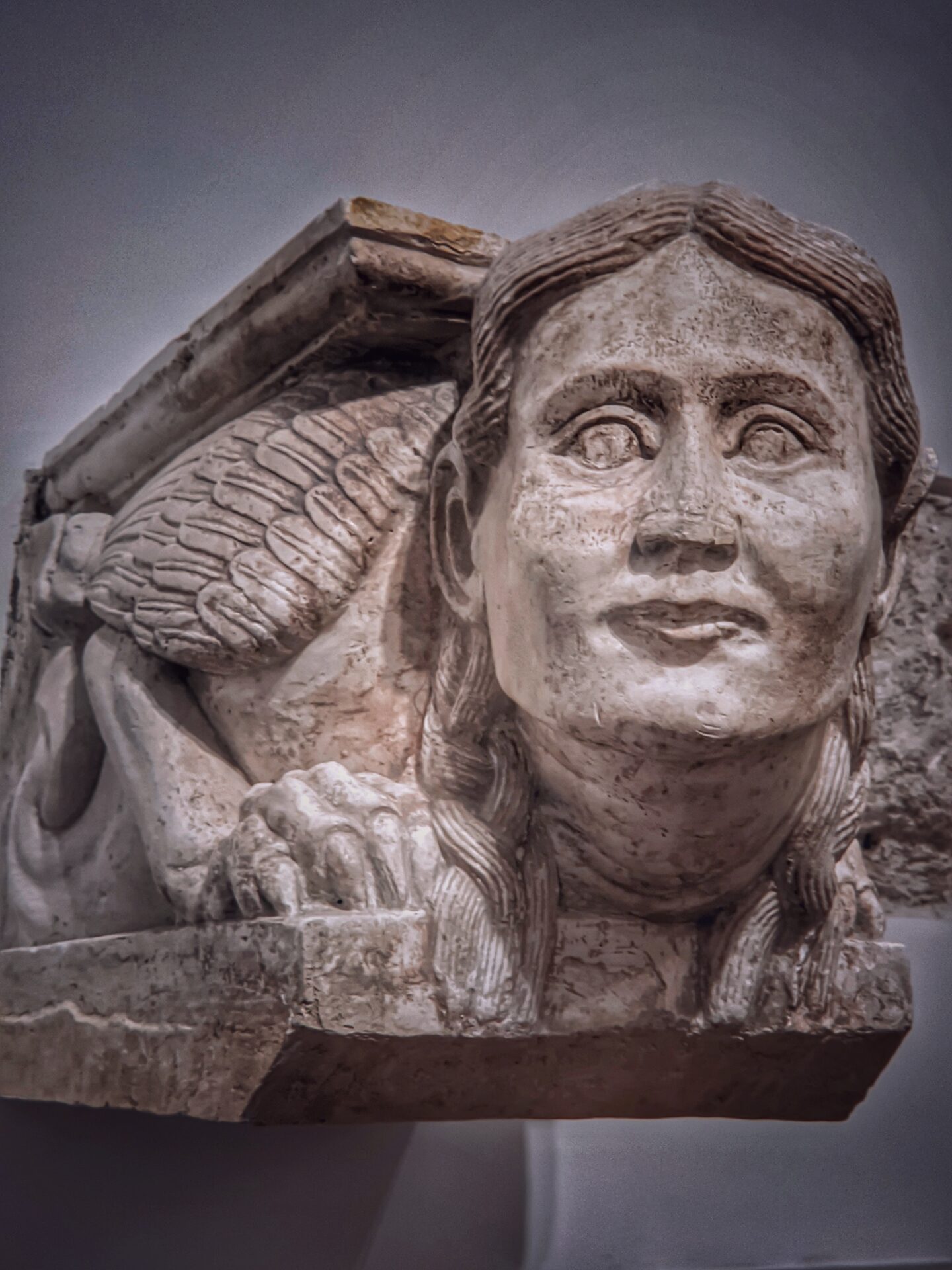a plaster cast with a winged figure and a large carved face in the gypsotheque of the castle of bari