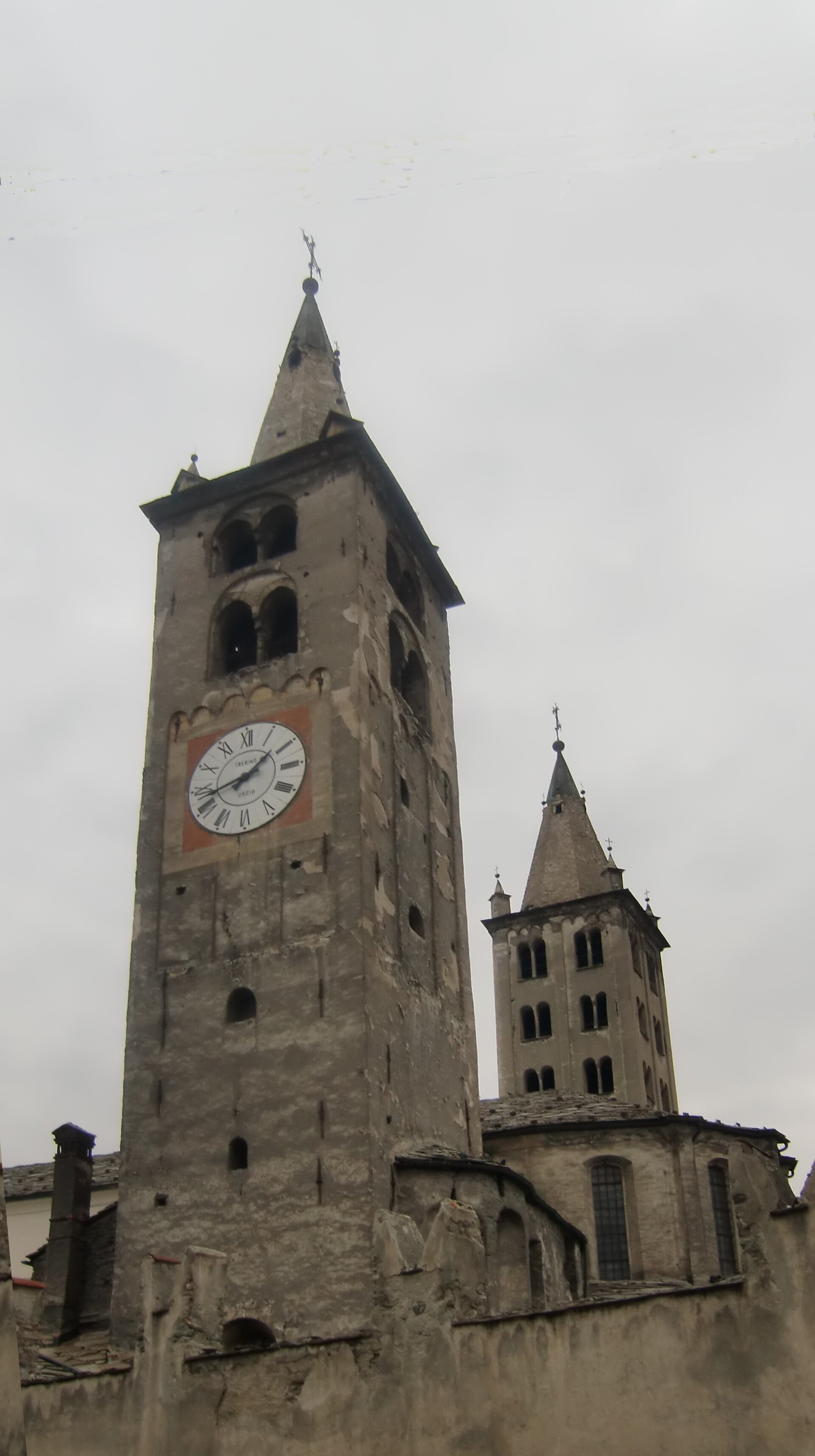 i due campanili romanici della cattedrale di aosta con le guglie in pietra sopra i tetti in lose