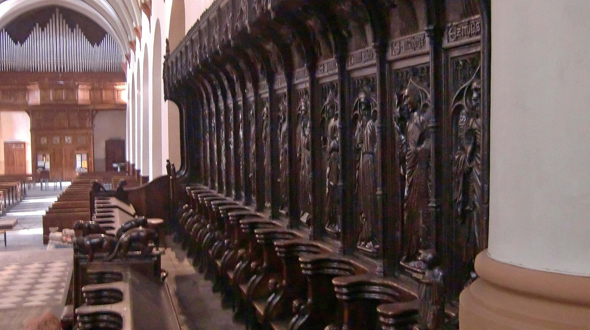 gli stalli del coro in legno intagliato della cattedrale di aosta, con le figure di santi sotto i baldacchini gotici