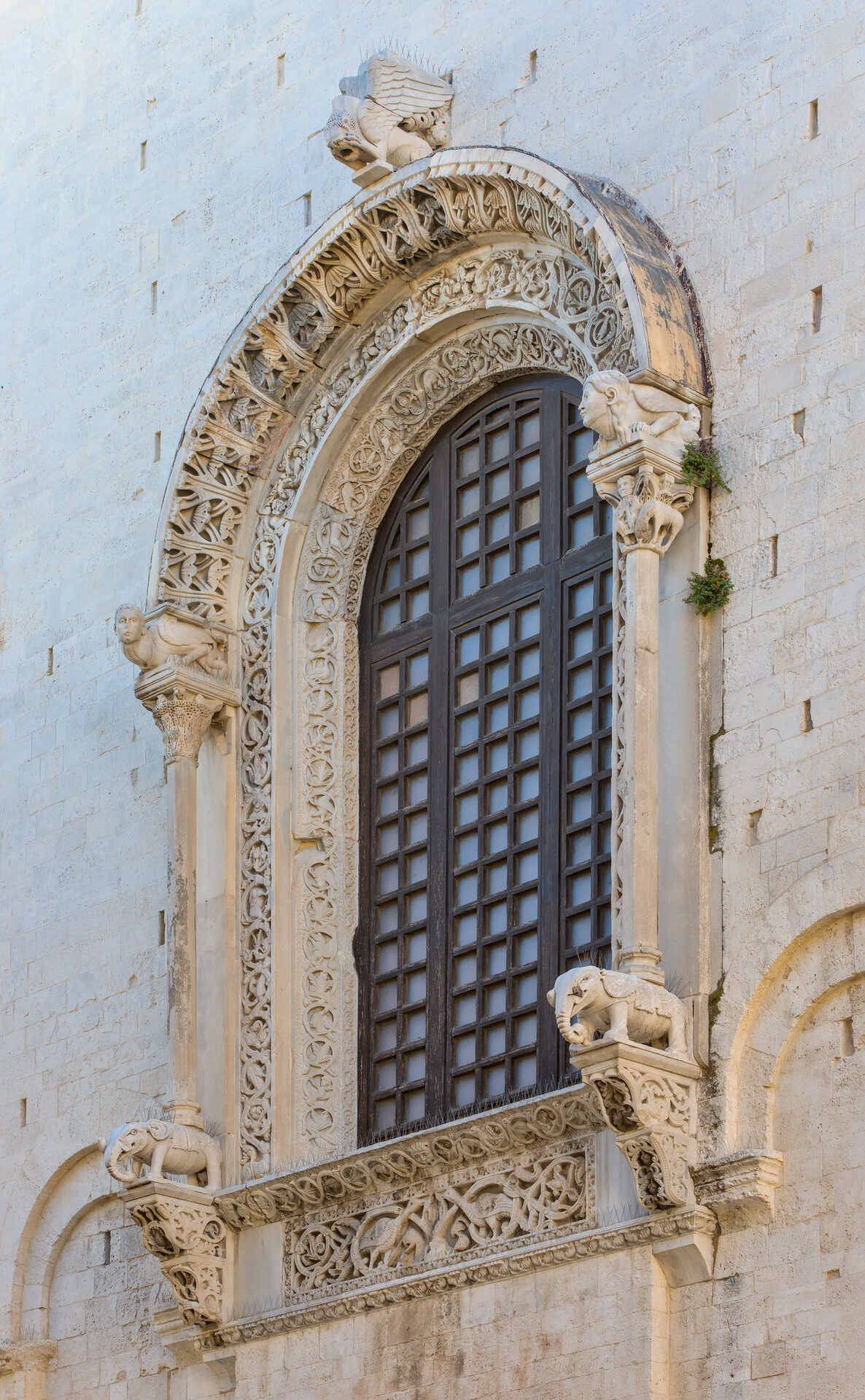 the apse window of the cathedral of san sabino in bari with its frame carved with scrolls and figures