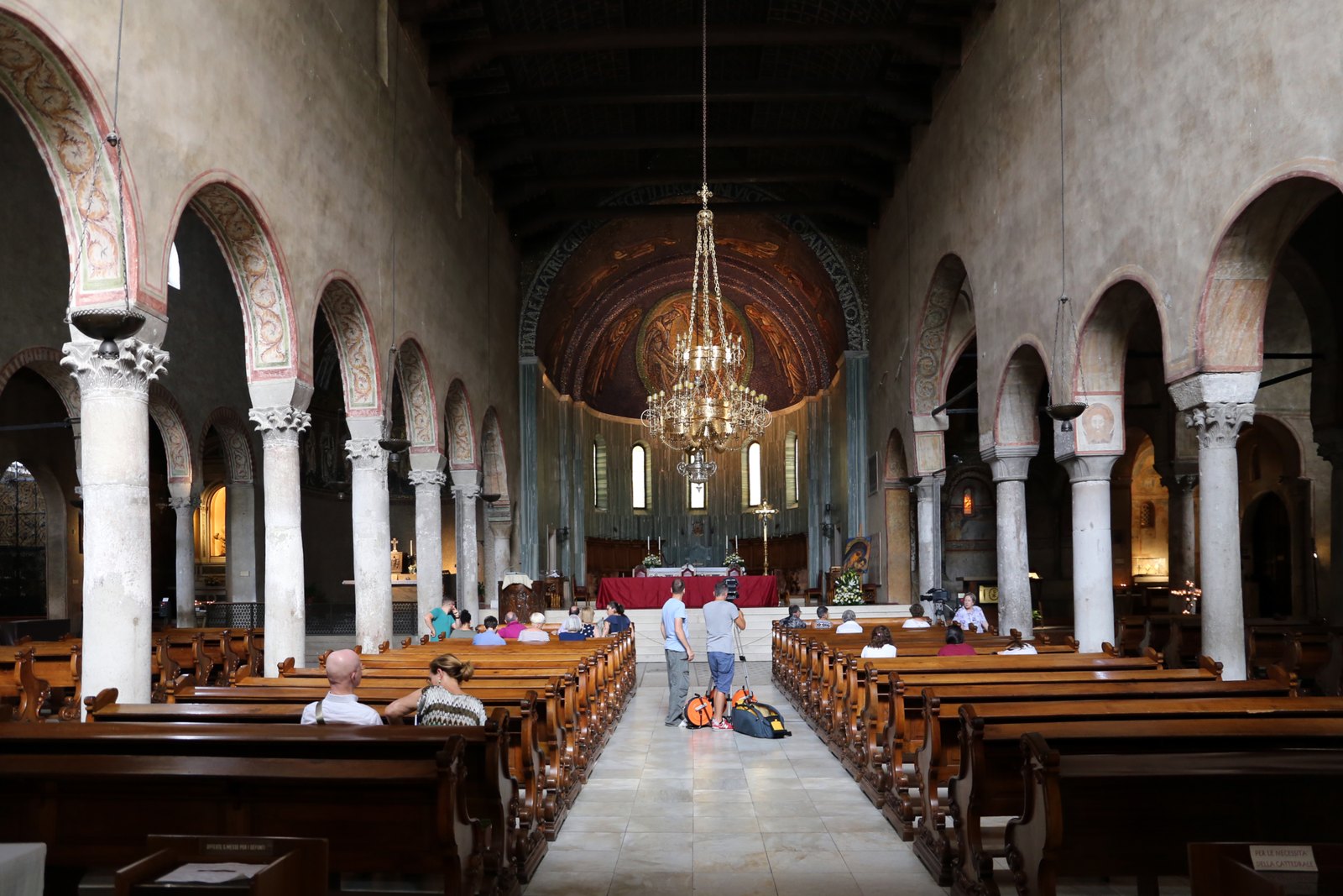 la navata centrale della cattedrale di san giusto con le colonne il soffitto a carena di nave e il lampadario