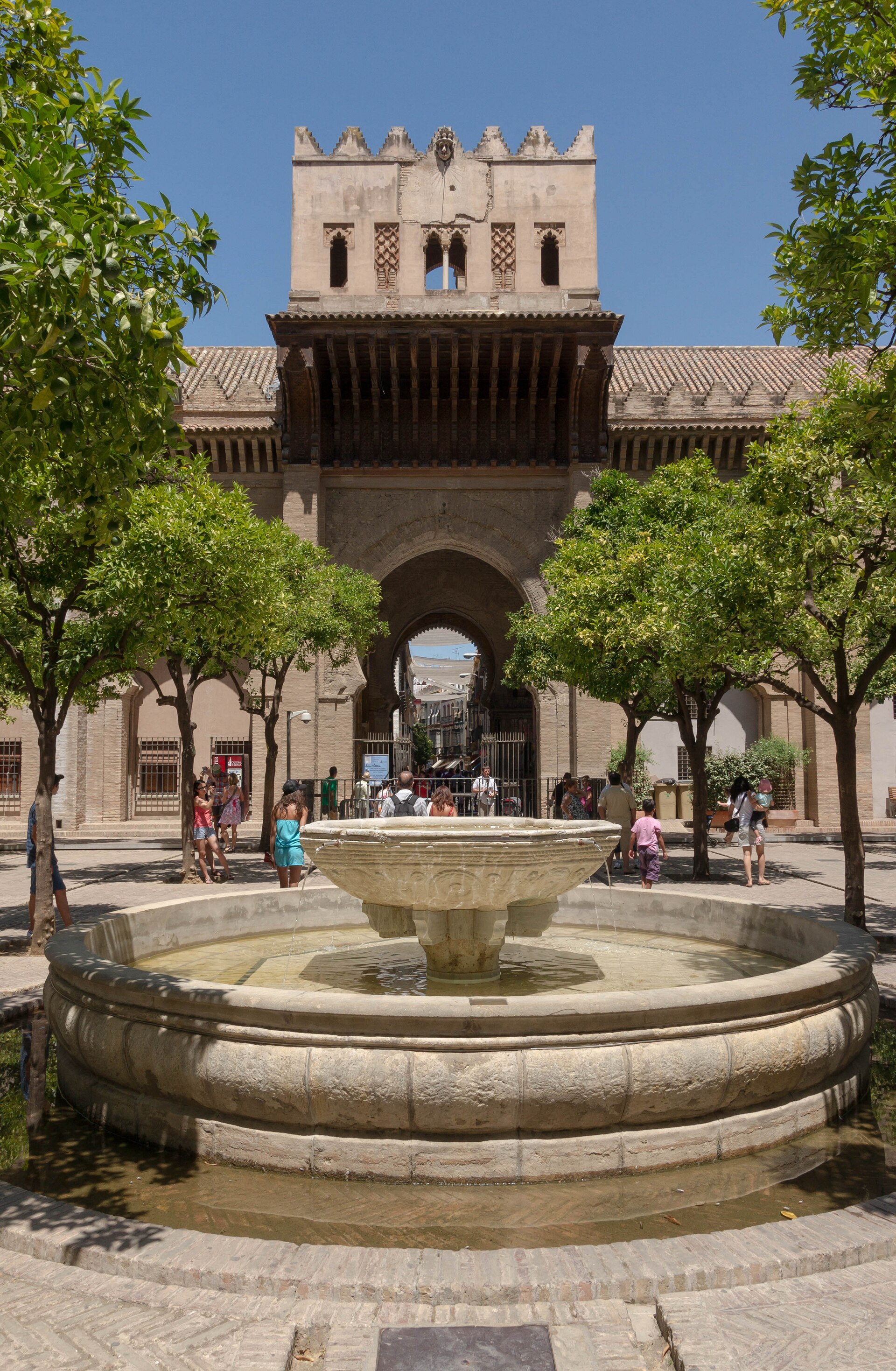 il patio de los naranjos della cattedrale di siviglia, con una fontana di pietra al centro, gli aranci e un portale ad arco sul fondo
