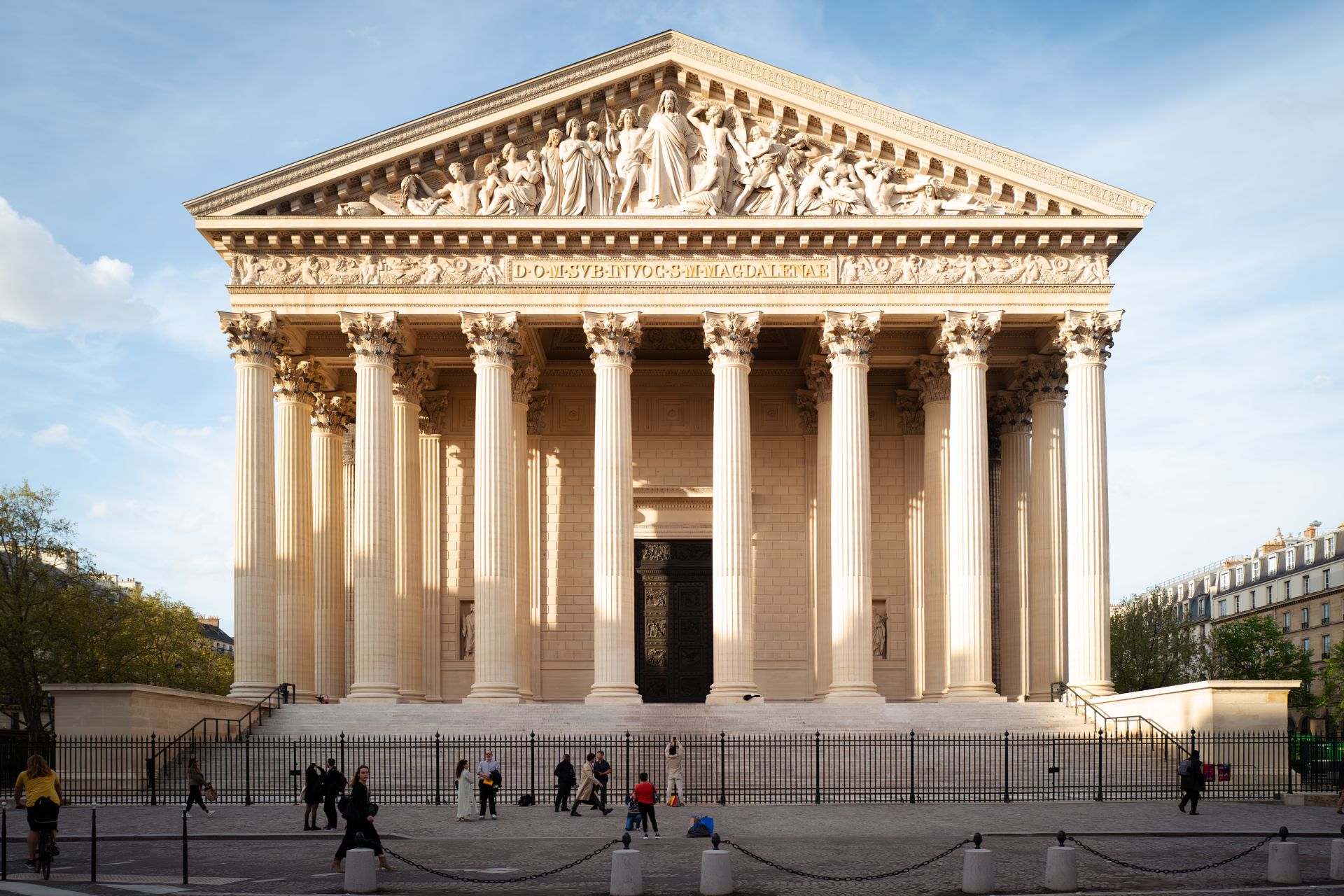 la facciata della chiesa della madeleine con il colonnato corinzio continuo, il frontone scolpito con il giudizio universale, la scalinata e nessuna croce visibile sul tetto