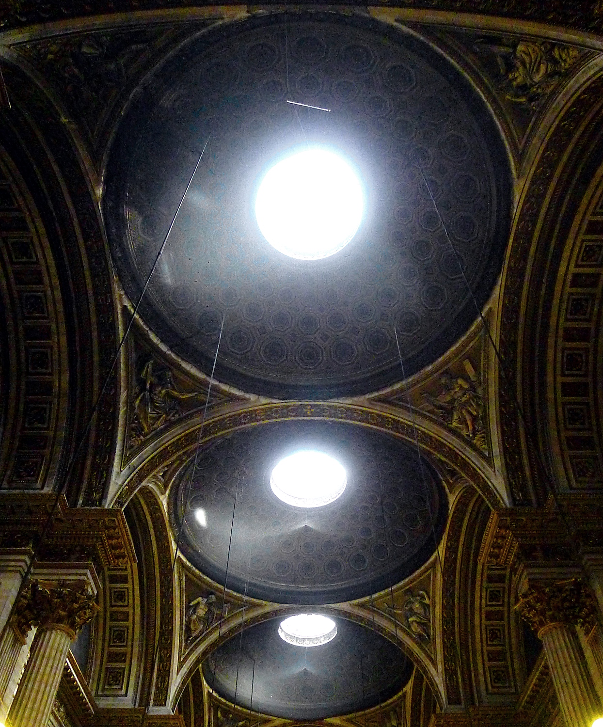 le tre cupole a cassettoni ottagonali della navata viste dal basso, ciascuna forata al centro da un lucernario rotondo che lascia filtrare la luce, con cornici dorate e capitelli corinzi agli angoli delle arcate