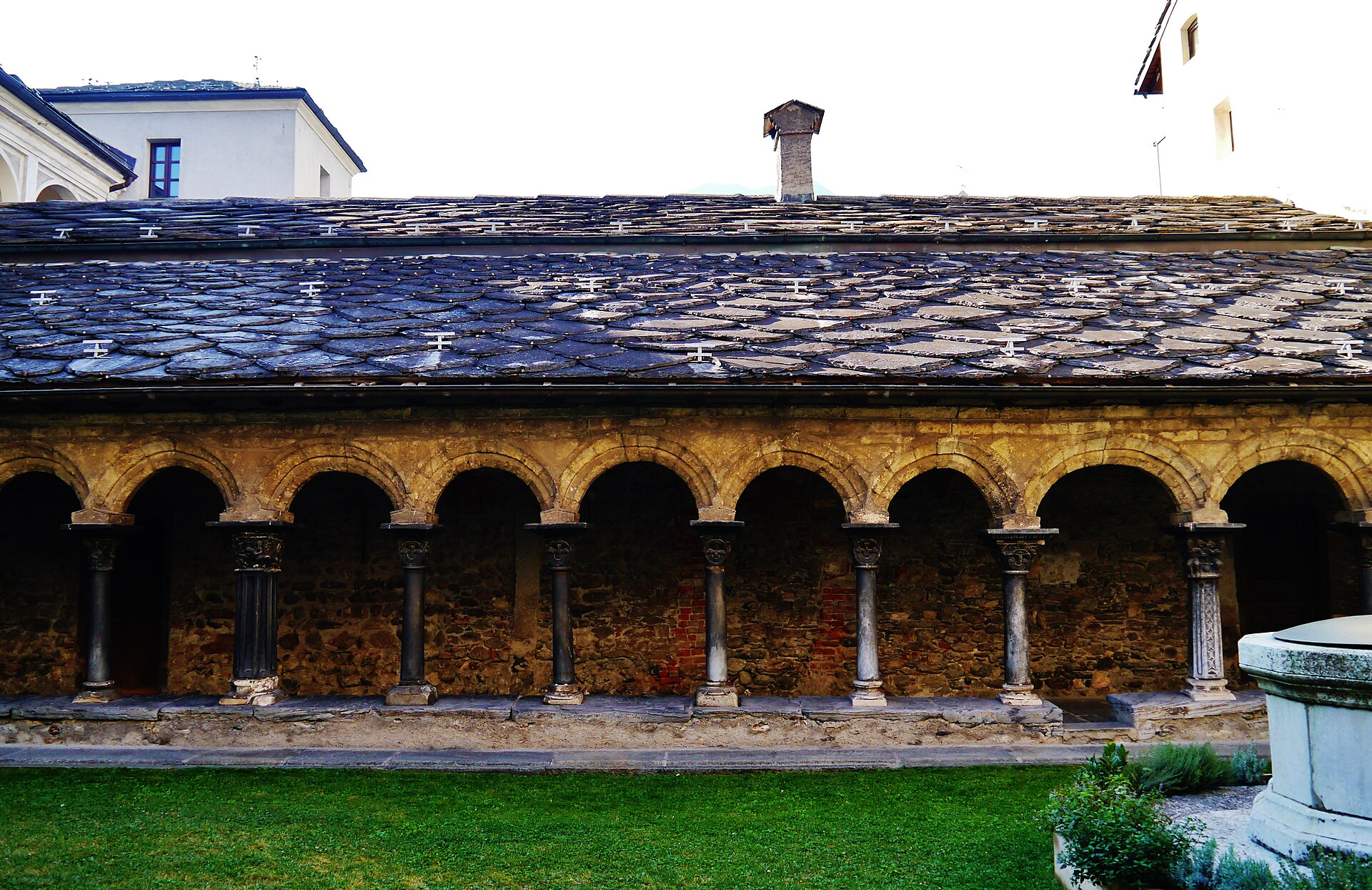 il chiostro romanico di sant orso ad aosta, con le arcate su colonne binate e il tetto in lose di pietra