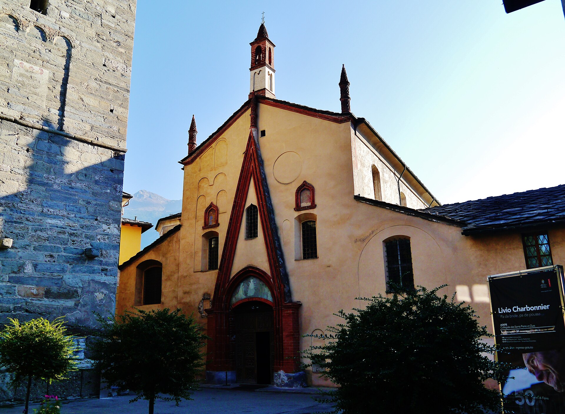 la facciata della collegiata di sant orso ad aosta, con il timpano gotico bordato di cotto rosso e il campanile romanico a sinistra