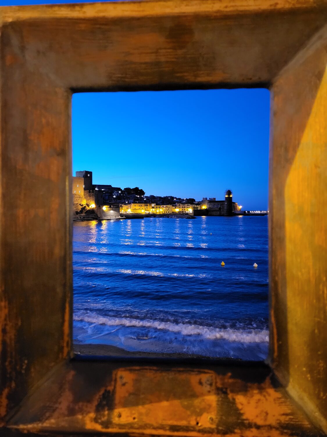 una delle cornici di bronzo dorato di Collioure che inquadra il castello e il campanile all’ora blu