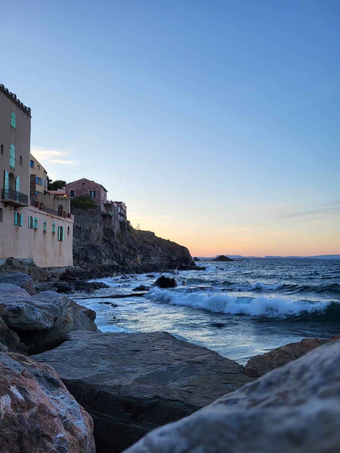 le case del quartiere del Mouré a Collioure sugli scogli, al tramonto, con il mare mosso