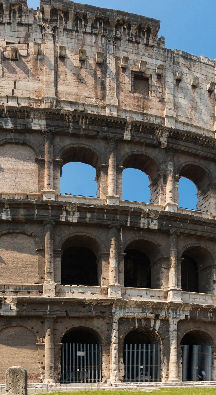 la facciata del Colosseo vista da vicino con i tre ordini sovrapposti di arcate e i fori lasciati dai perni di bronzo