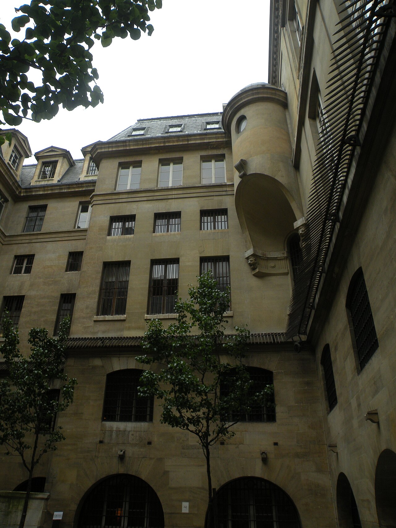 il cortile delle donne visto dal basso verso il cielo, con tre piani di finestre sbarrate da inferriate, una torretta rotonda all angolo, un tetto di ardesia con abbaini e due alberelli nel cortile