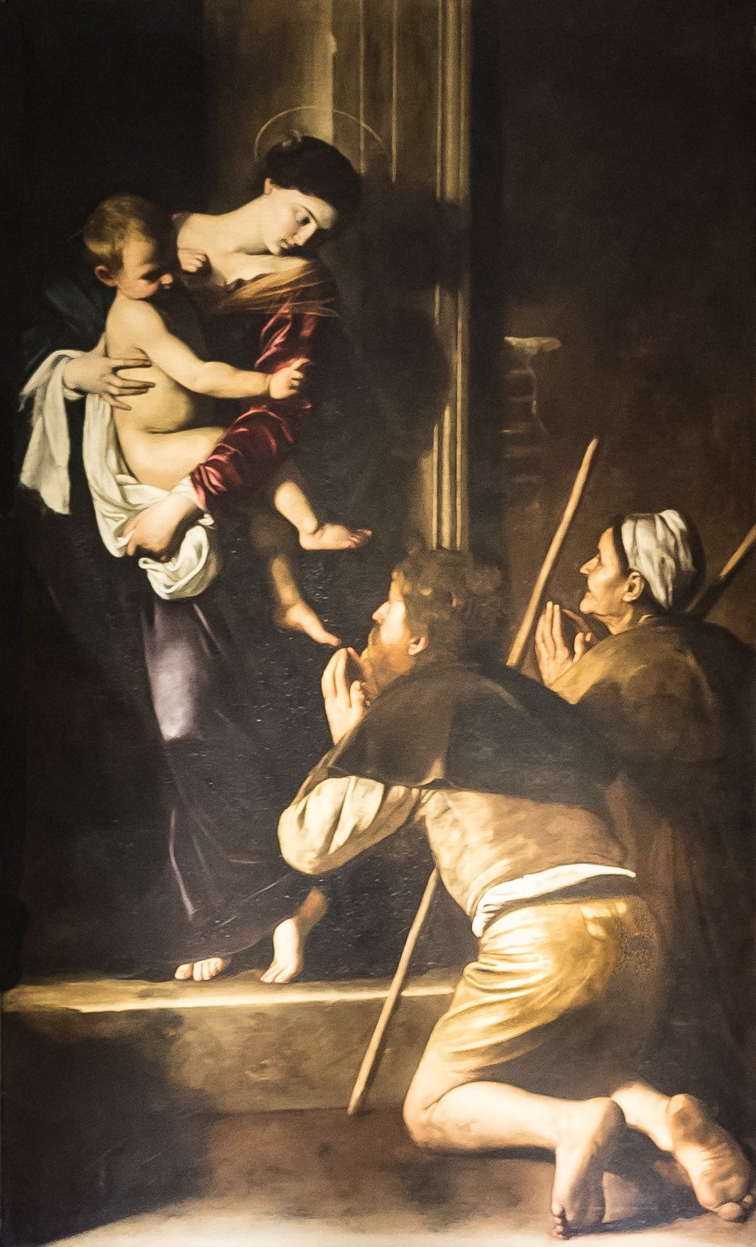 la madonna dei pellegrini di caravaggio con i due pellegrini inginocchiati e i piedi sporchi in primo piano