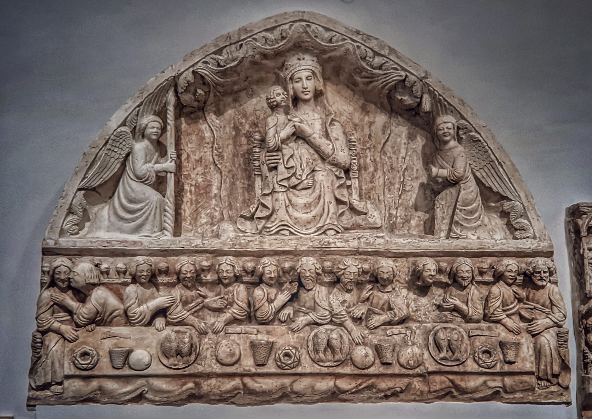a plaster cast of an apulian romanesque lunette in the gypsotheque of the swabian castle of bari, with the enthroned virgin and a last supper below