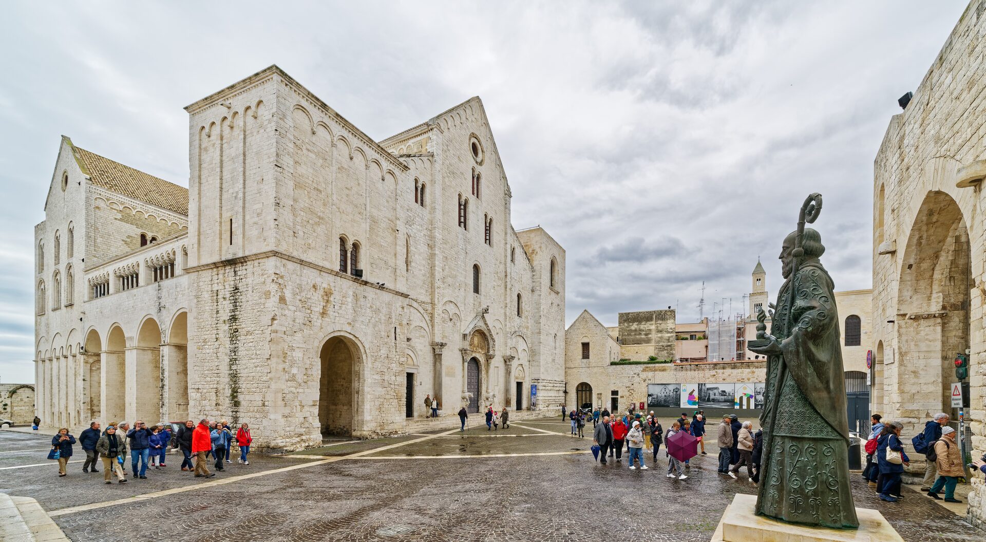 the basilica of san nicola in bari seen from the square with its southern flank and the bronze statue of the saint