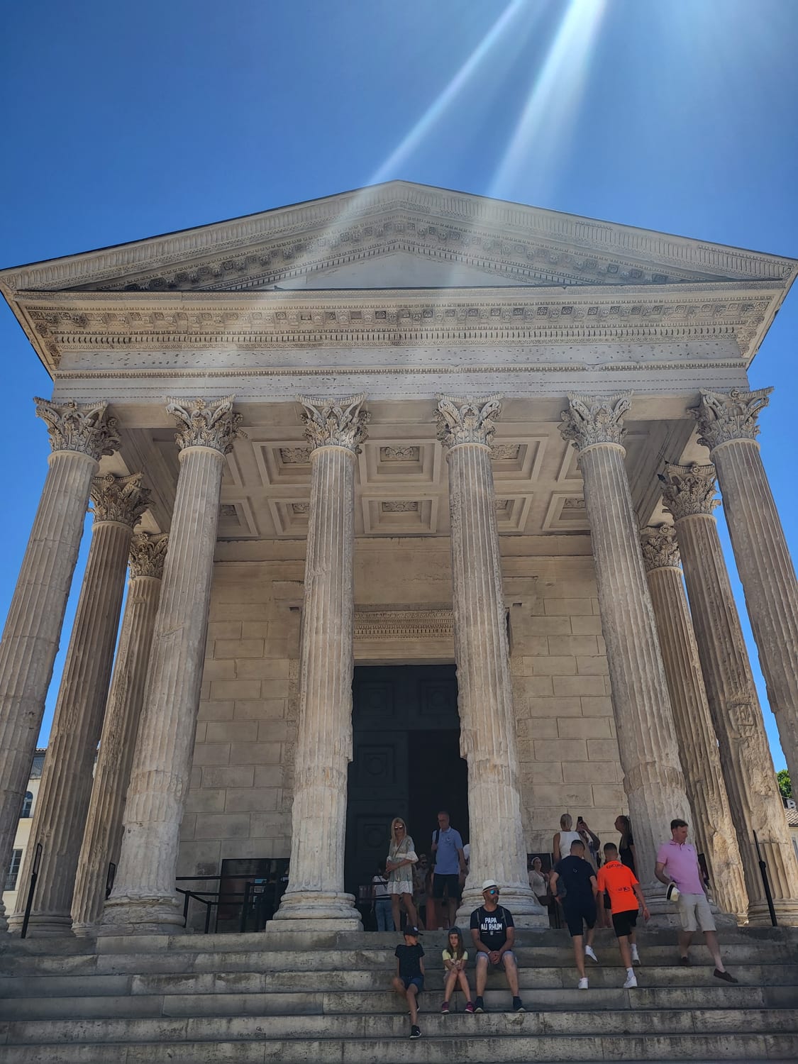 las columnas corintias y el frontón de la Maison Carrée de Nimes vistos desde abajo, desde la escalinata