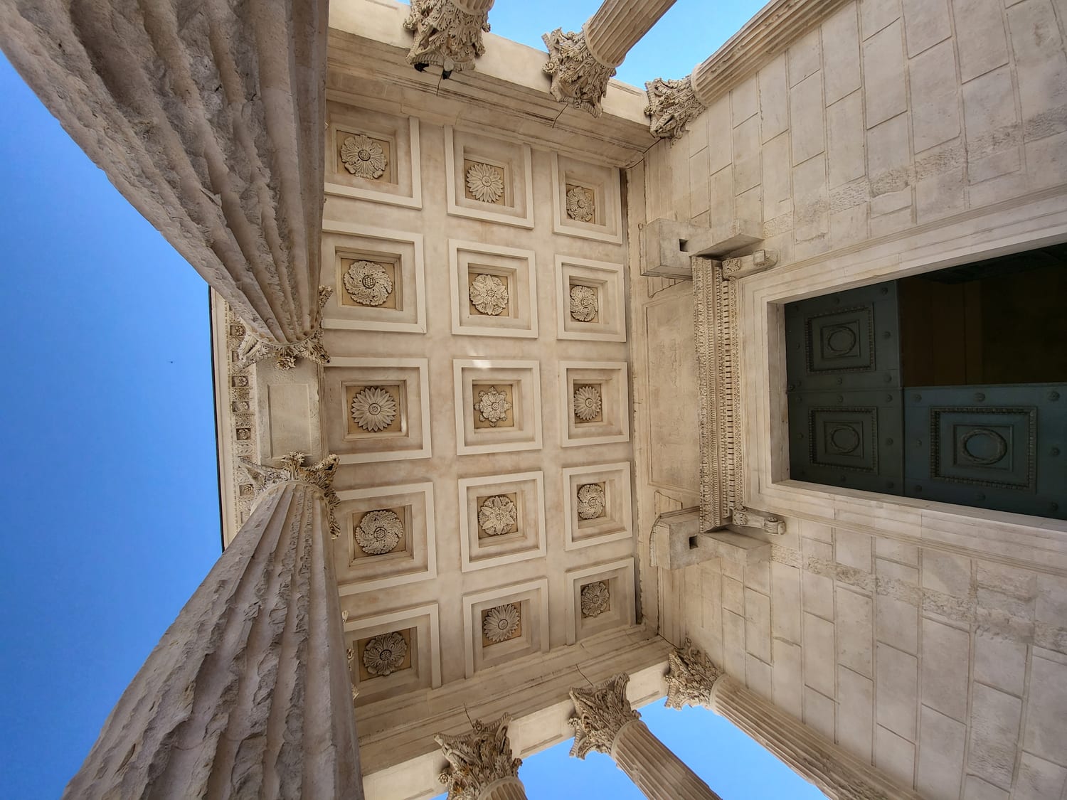 el techo artesonado del pórtico de la Maison Carrée de Nimes, con sus rosetones esculpidos, visto desde abajo