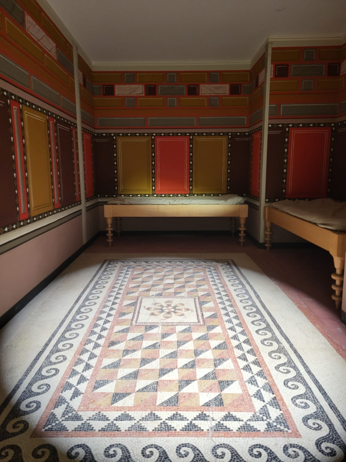 la reconstrucción de una habitación romana en el Musée de la Romanité de Nimes, con las paredes pintadas a paneles rojos y amarillos y el suelo de mosaico