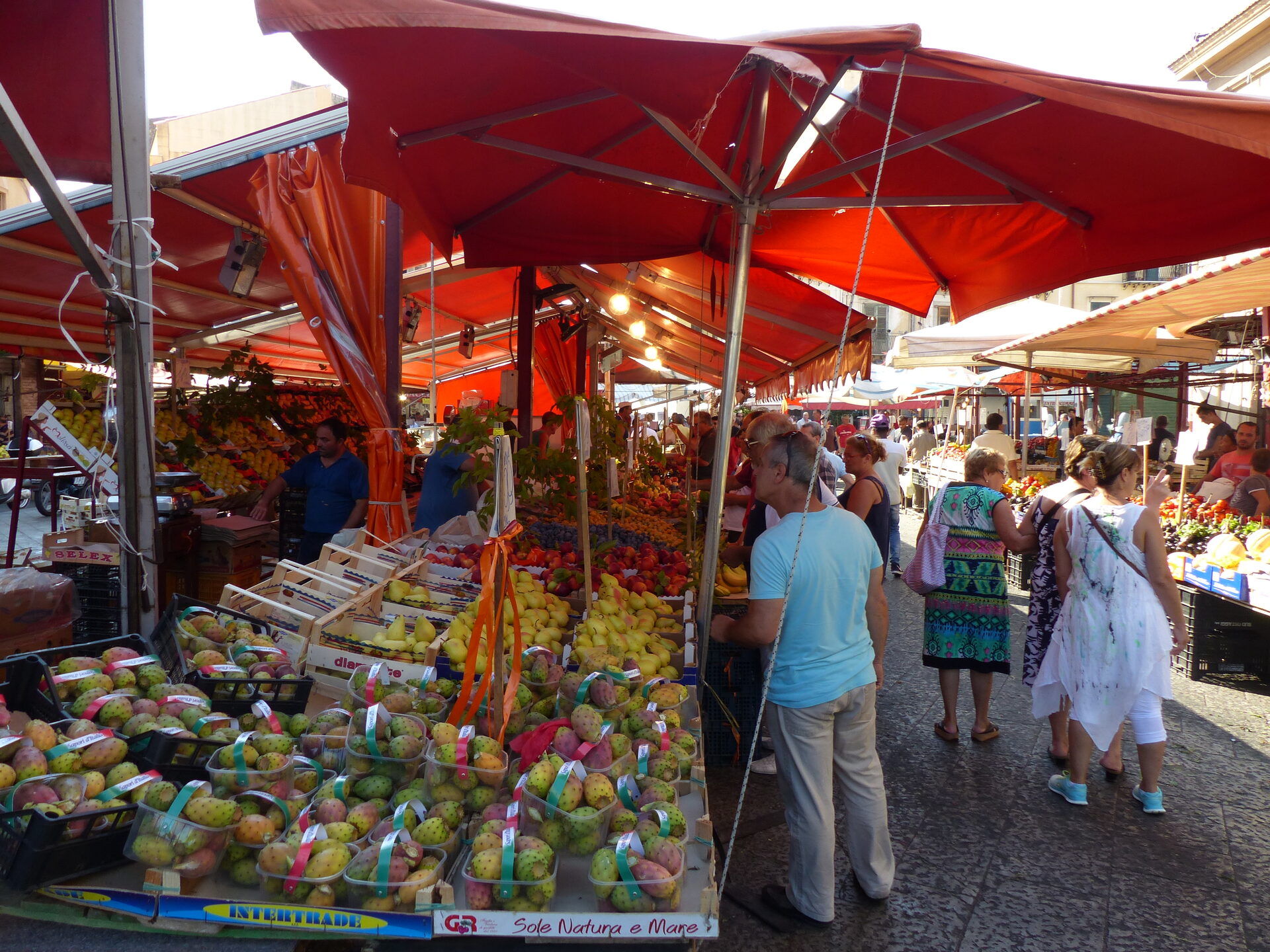 the ballaro market in palermo with the fruit stalls the red umbrellas and people shopping