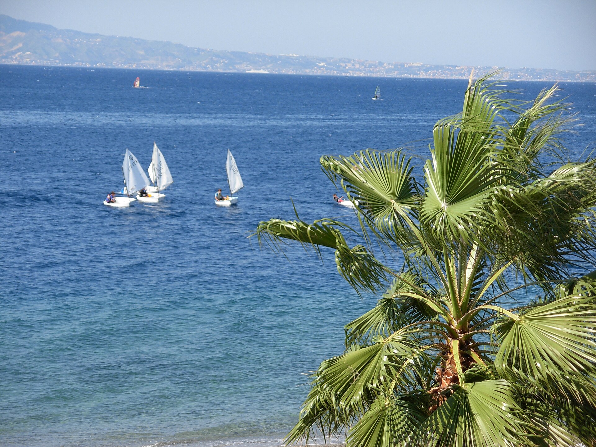 il mare dello stretto di messina davanti a reggio calabria con le vele e la costa siciliana sullo sfondo