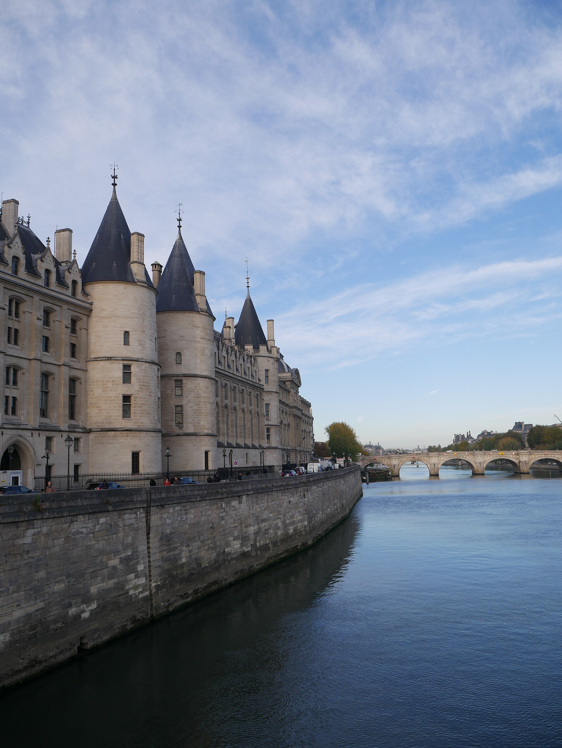 le torri rotonde della conciergerie con i tetti conici di ardesia sul lungosenna di parigi, il muro di banchina, il fiume e il pont neuf con le sue arcate sullo sfondo