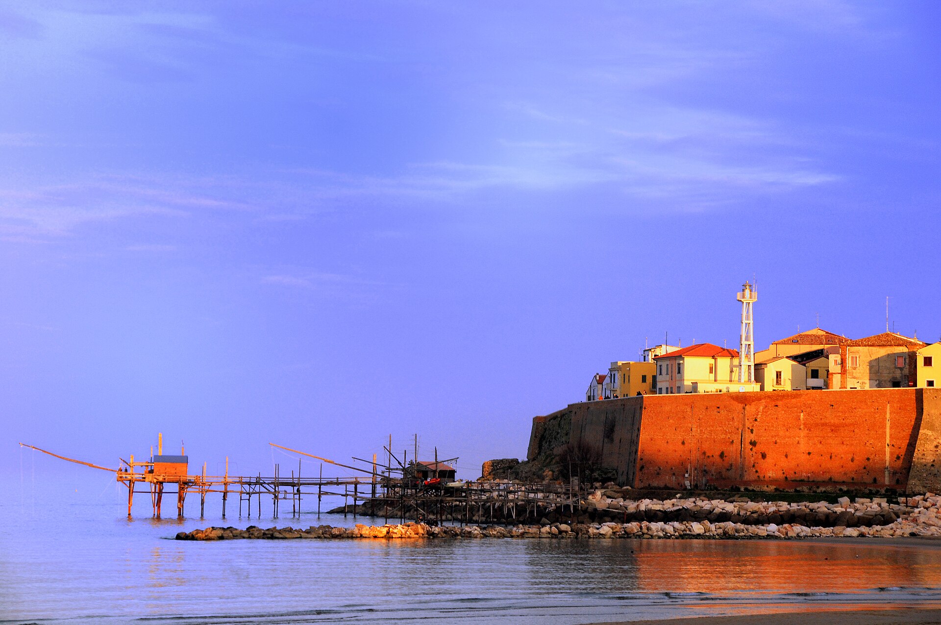 il borgo antico di termoli sulla scogliera al tramonto con un trabucco in primo piano