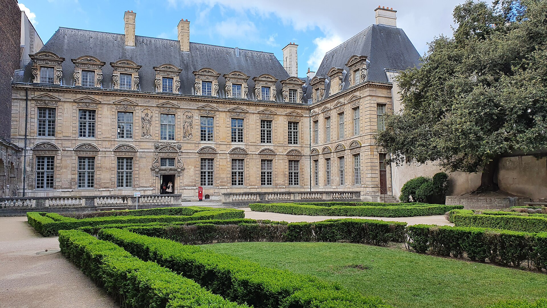 il cortile dell hotel de sully a parigi, la facciata di pietra chiara con le allegorie scolpite fra le finestre e i riquadri di bosso potato del giardino alla francese