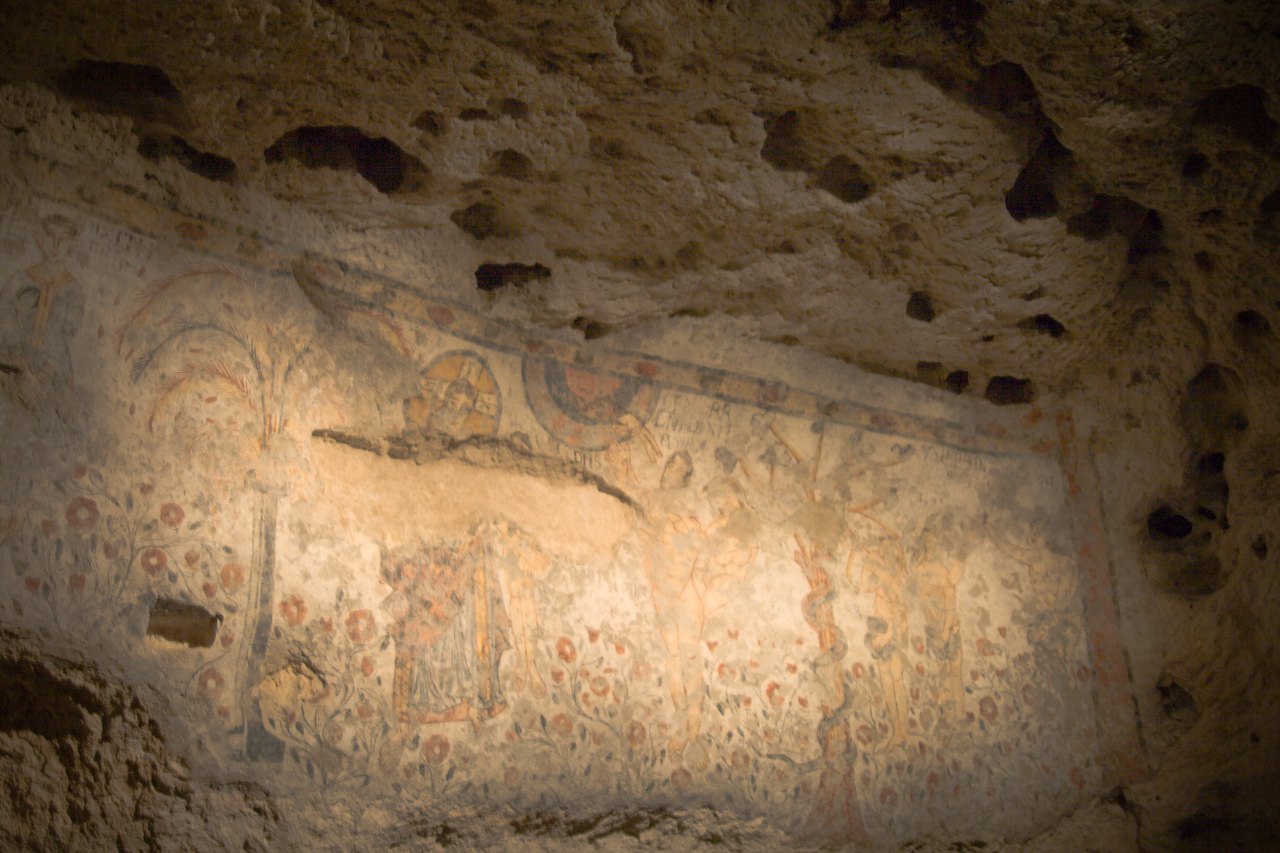 les fresques de la crypte du peche originel avec les figures et les fleurs rouges peintes a leurs pieds