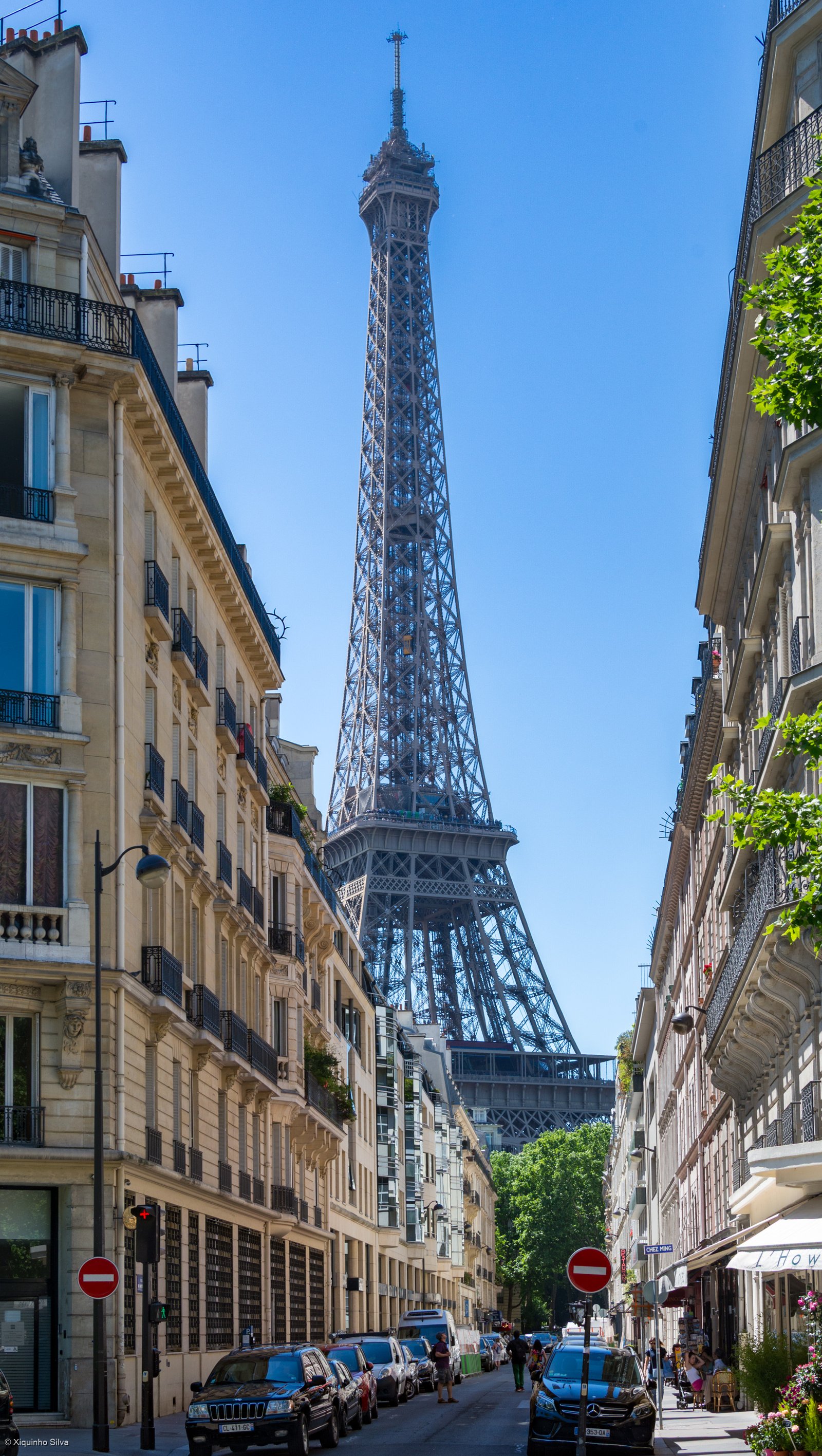 una via del settimo arrondissement di parigi fiancheggiata da palazzi color crema, con la tour eiffel visibile in fondo alla strada
