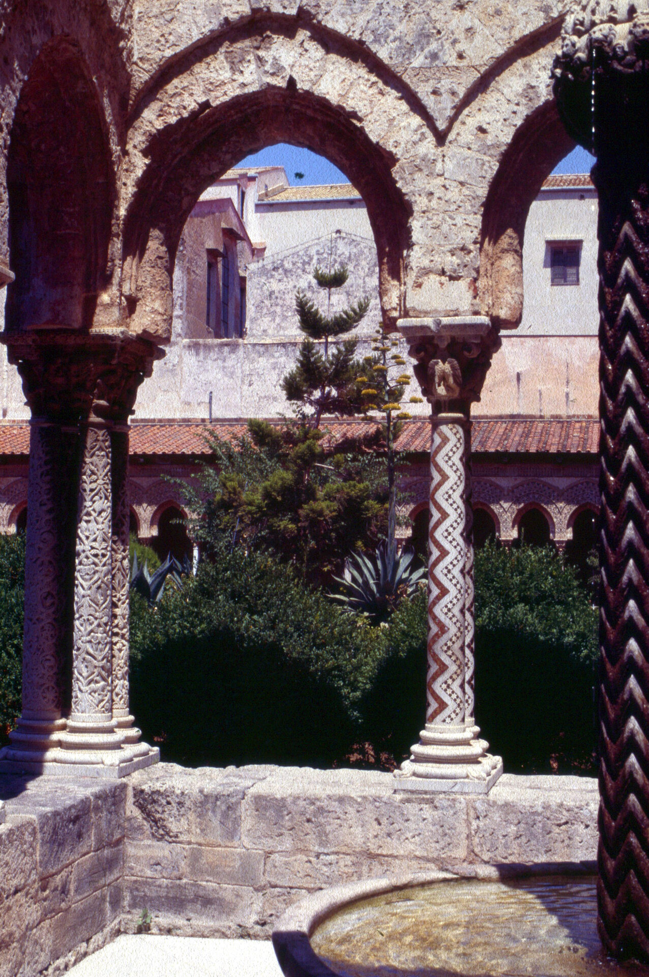 the fountain of the monreale cloister inside its enclosure of columns with the scaled shaft