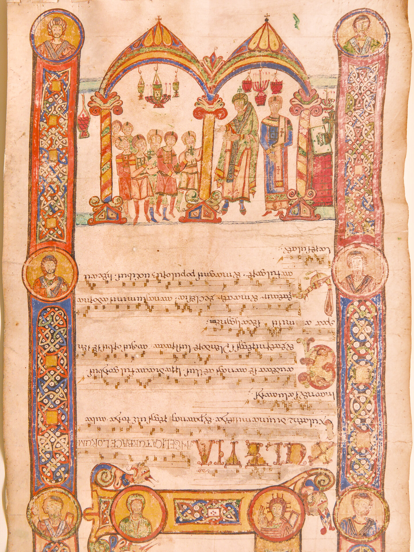 a miniature from a bari exultet with a liturgical scene under a ciborium and medallions with busts of saints in the border