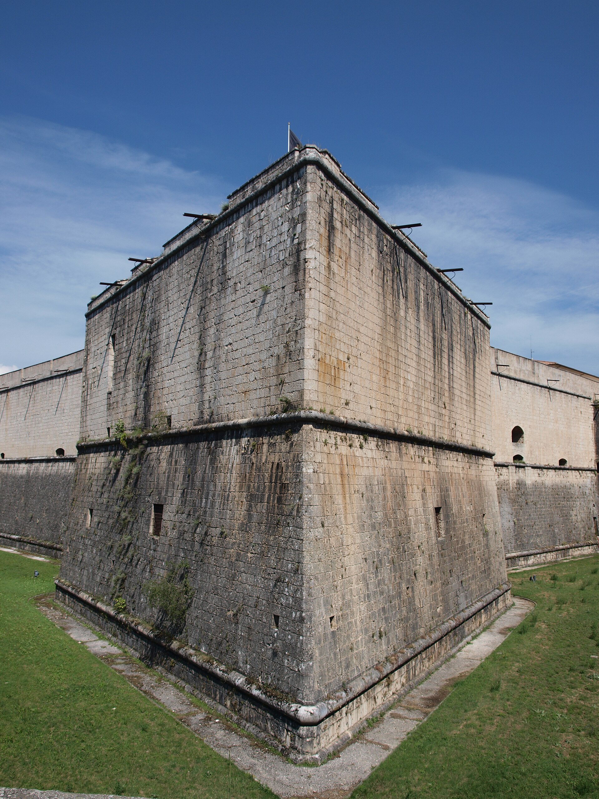 un bastione alto del forte spagnolo visto dal ponte con il fossato erboso la controscarpa e il gran sasso in fondo