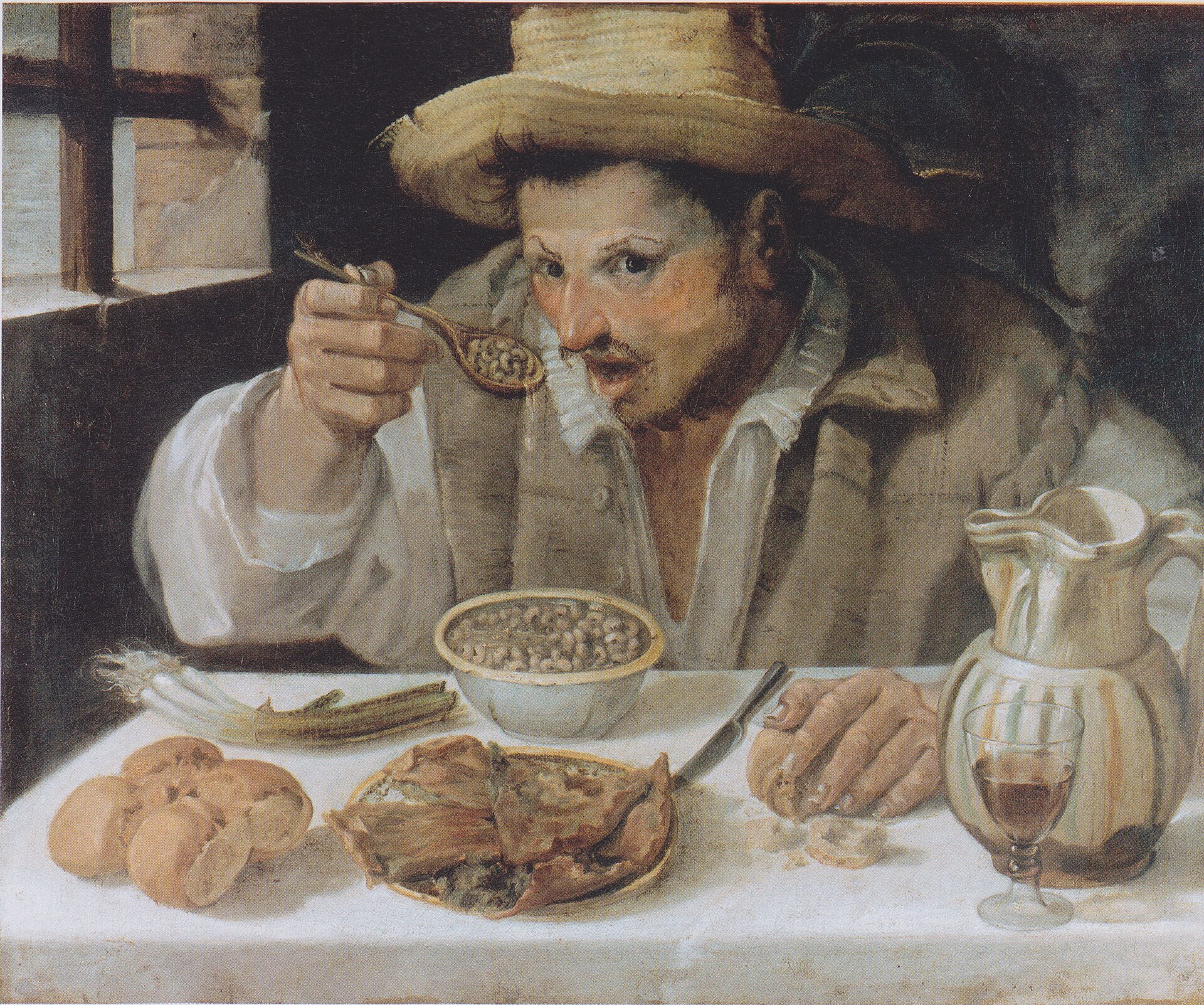 il mangiafagioli di annibale carracci, un uomo con il cappello di paglia che porta alla bocca un cucchiaio di fagioli guardando verso chi osserva, con pane, cipollotti, una torta salata e una brocca sul tavolo