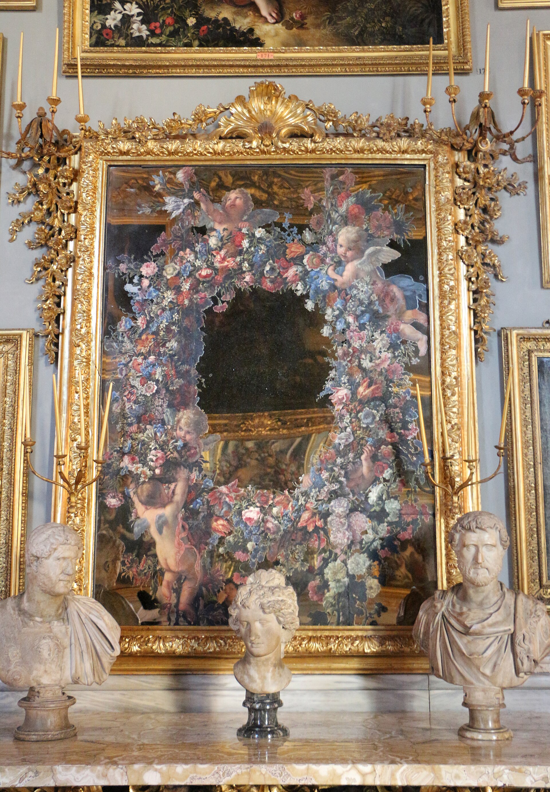 uno specchio dipinto della galleria colonna con una ghirlanda di fiori e cinque amorini sul vetro, in cui si riflettono le cornici dorate della sala, sopra tre busti antichi