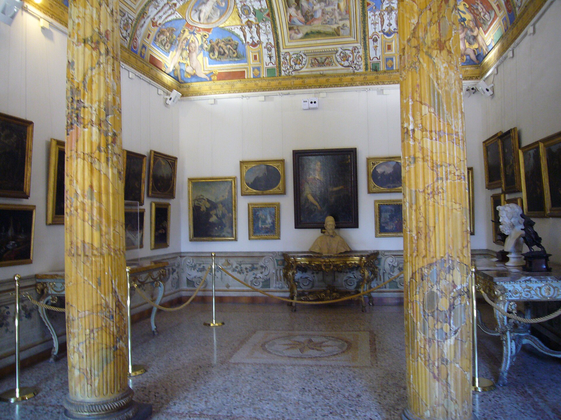 la stanza di palazzo corsini in cui mori cristina di svezia, con due colonne a finto marmo giallo, il soffitto affrescato e le pareti coperte di quadri